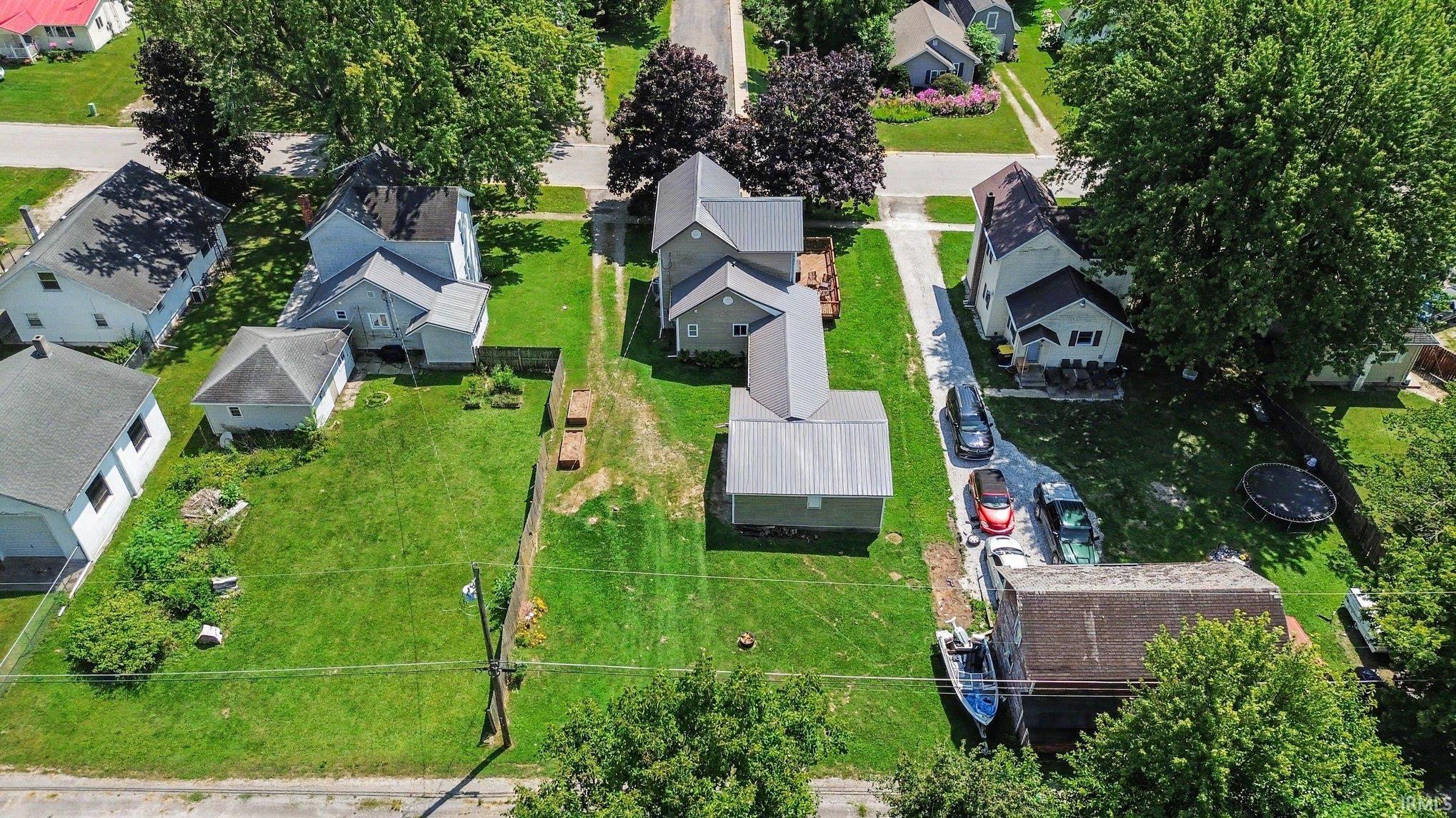 Expansive lot featuring a primary residence with a gray roof and light-colored siding, accompanied by a detached garage structure