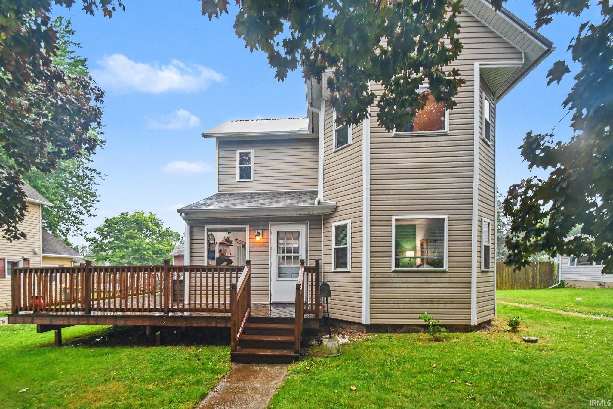 Multi-level siding home featuring a spacious wood deck, white trim windows, and a prominent side extension