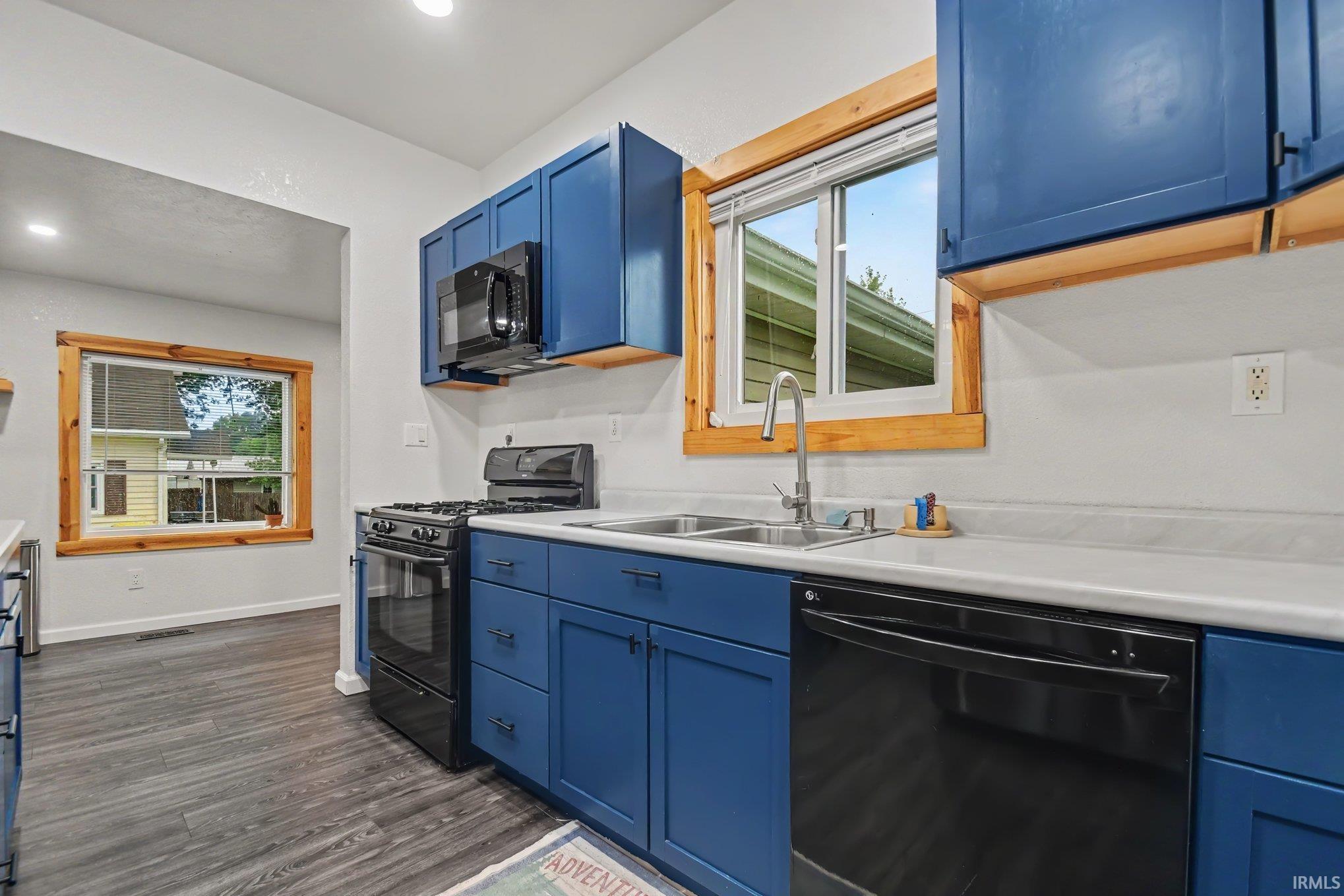 Kitchen featuring blue cabinetry, white countertops, and black appliances