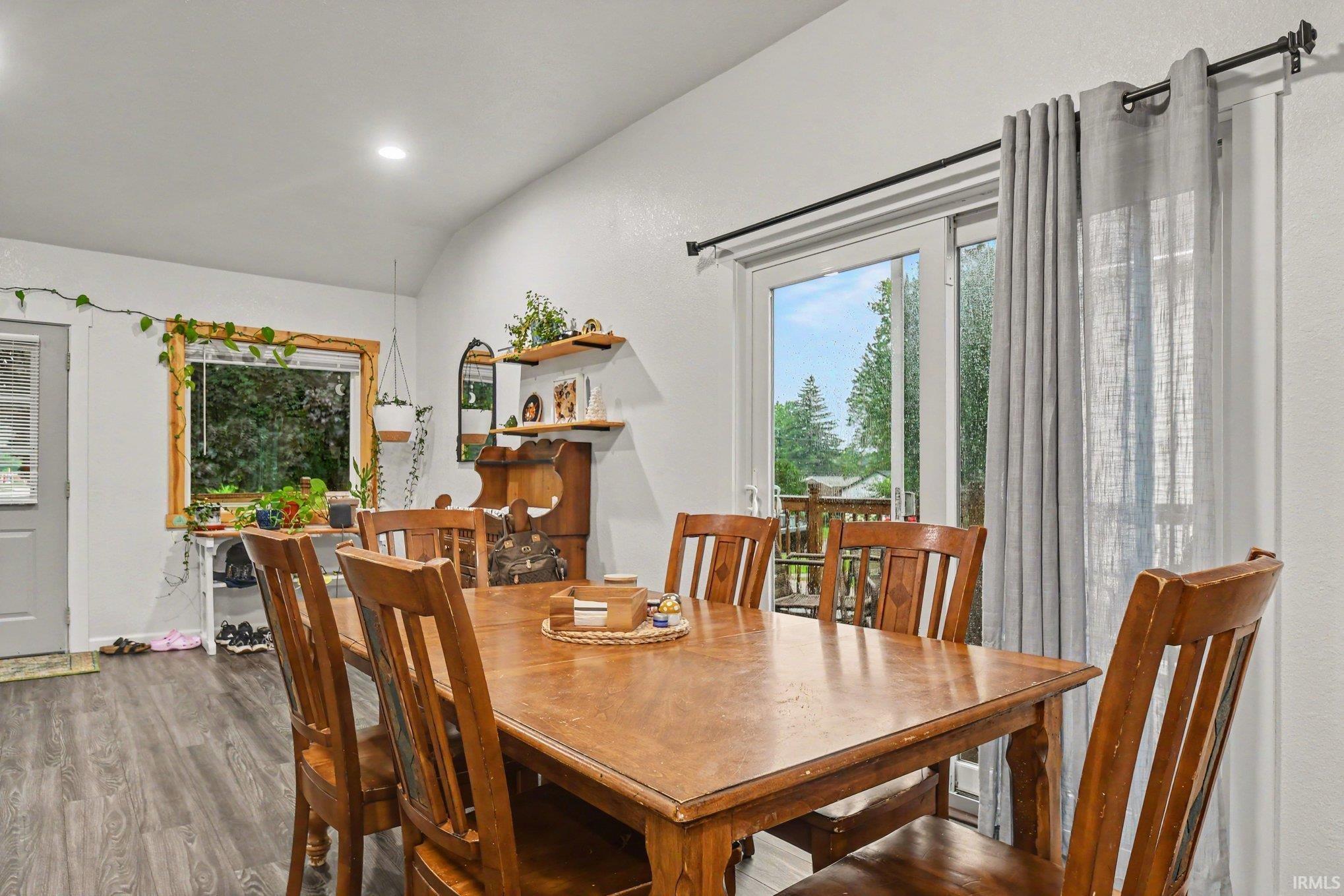 Dining area featuring wood-finish flooring, a large sliding glass door, a bright window with wood trim, and recessed lighting