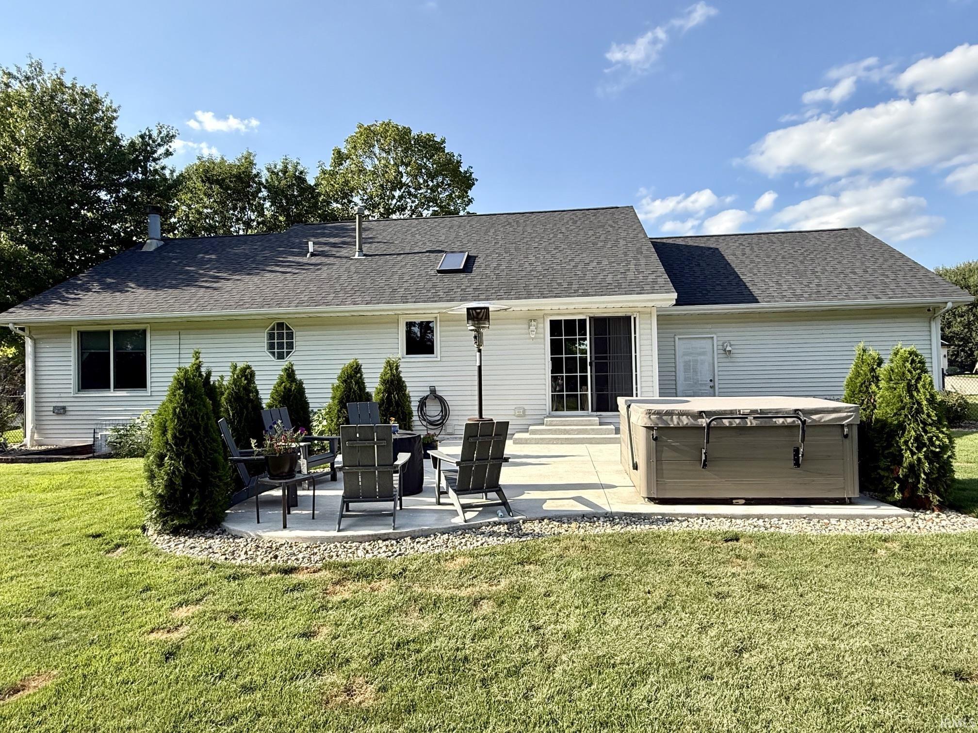 Expansive rear exterior featuring white siding, a multi-level concrete patio, and a shingled roof