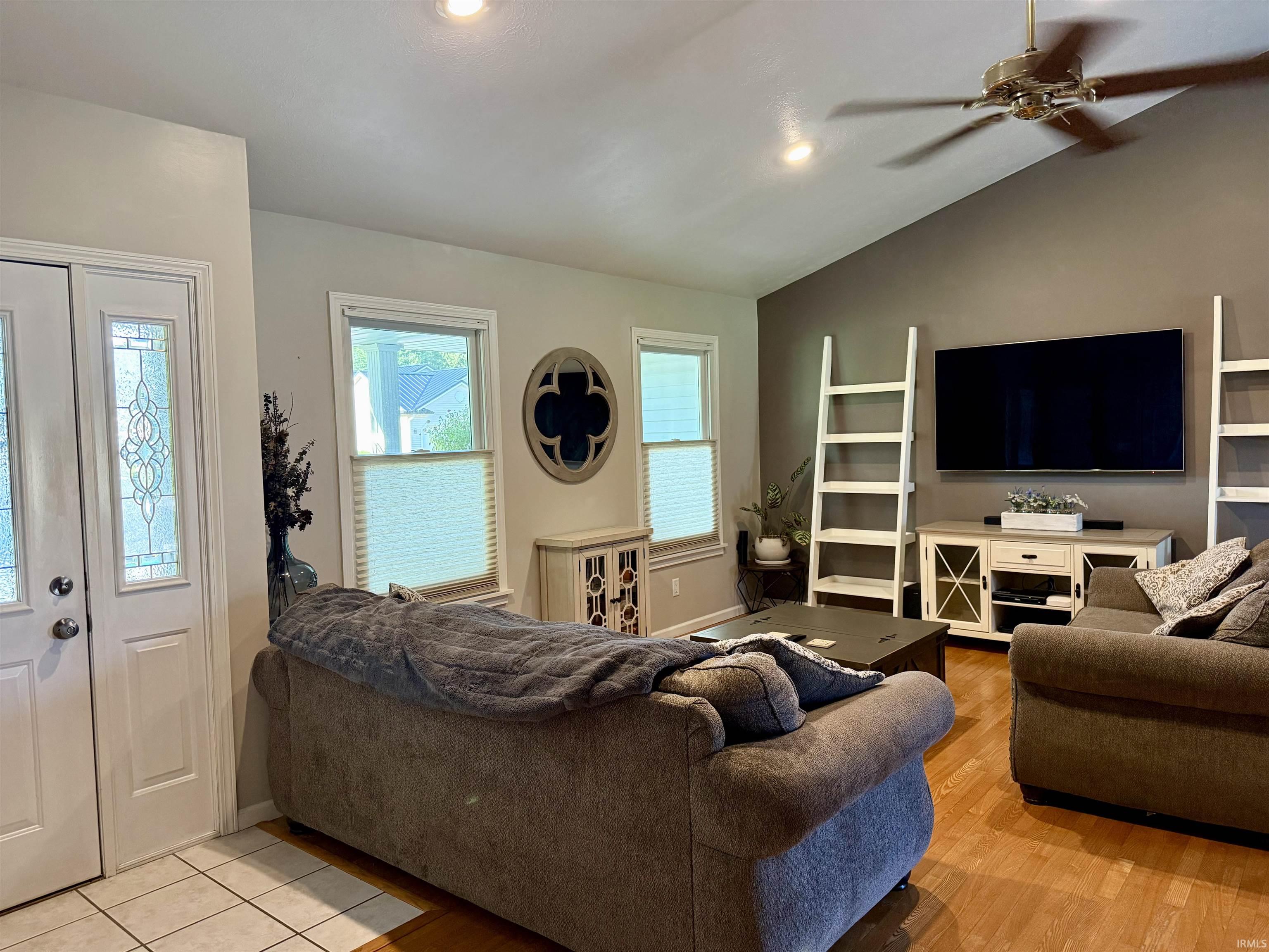 Living area featuring vaulted ceilings, recessed lighting, wood-finish flooring, a ceiling fan, and double entry doors with decorative glass inserts
