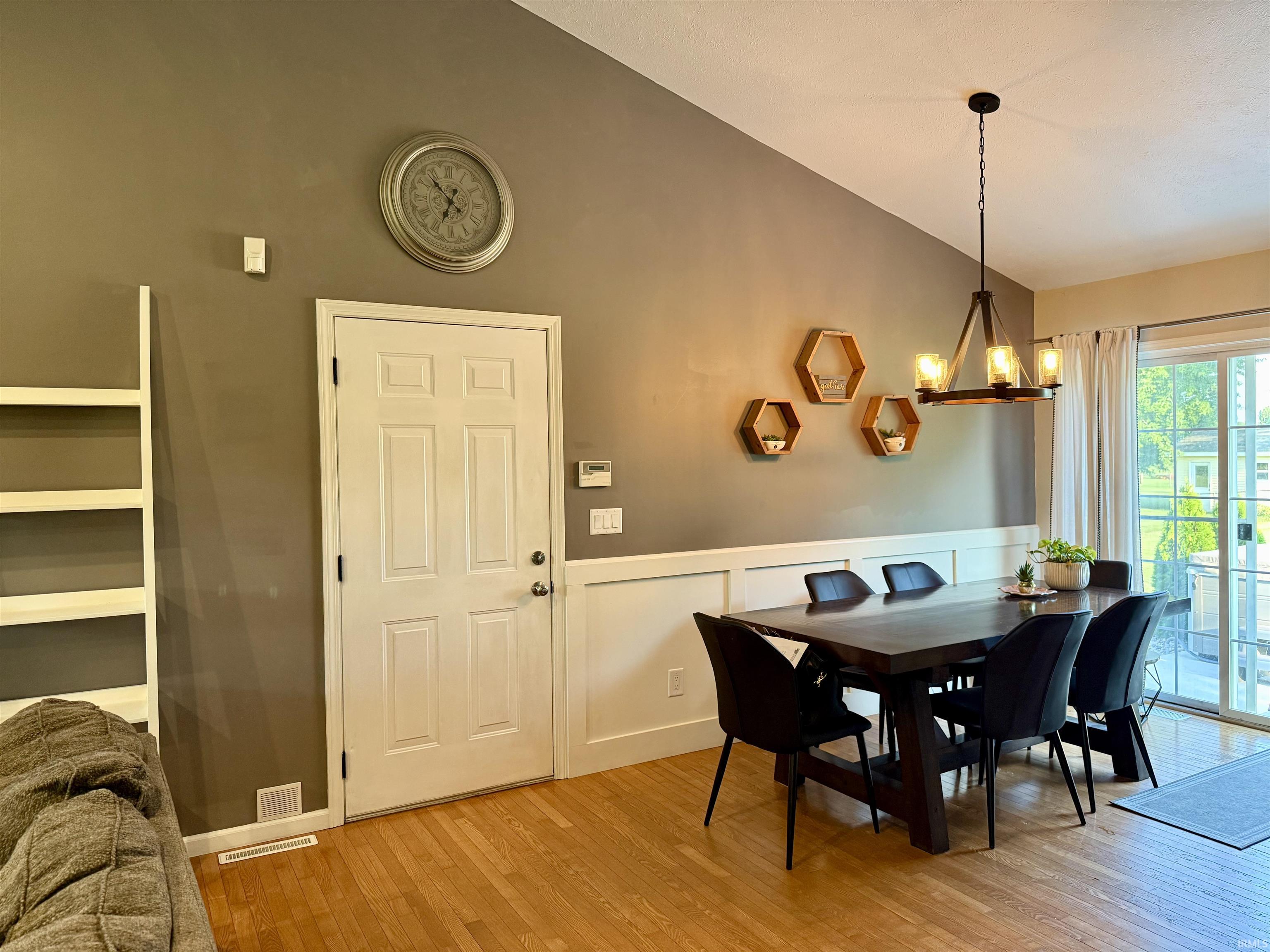 Dining area featuring wood-finish flooring, a vaulted ceiling, and sliding glass doors