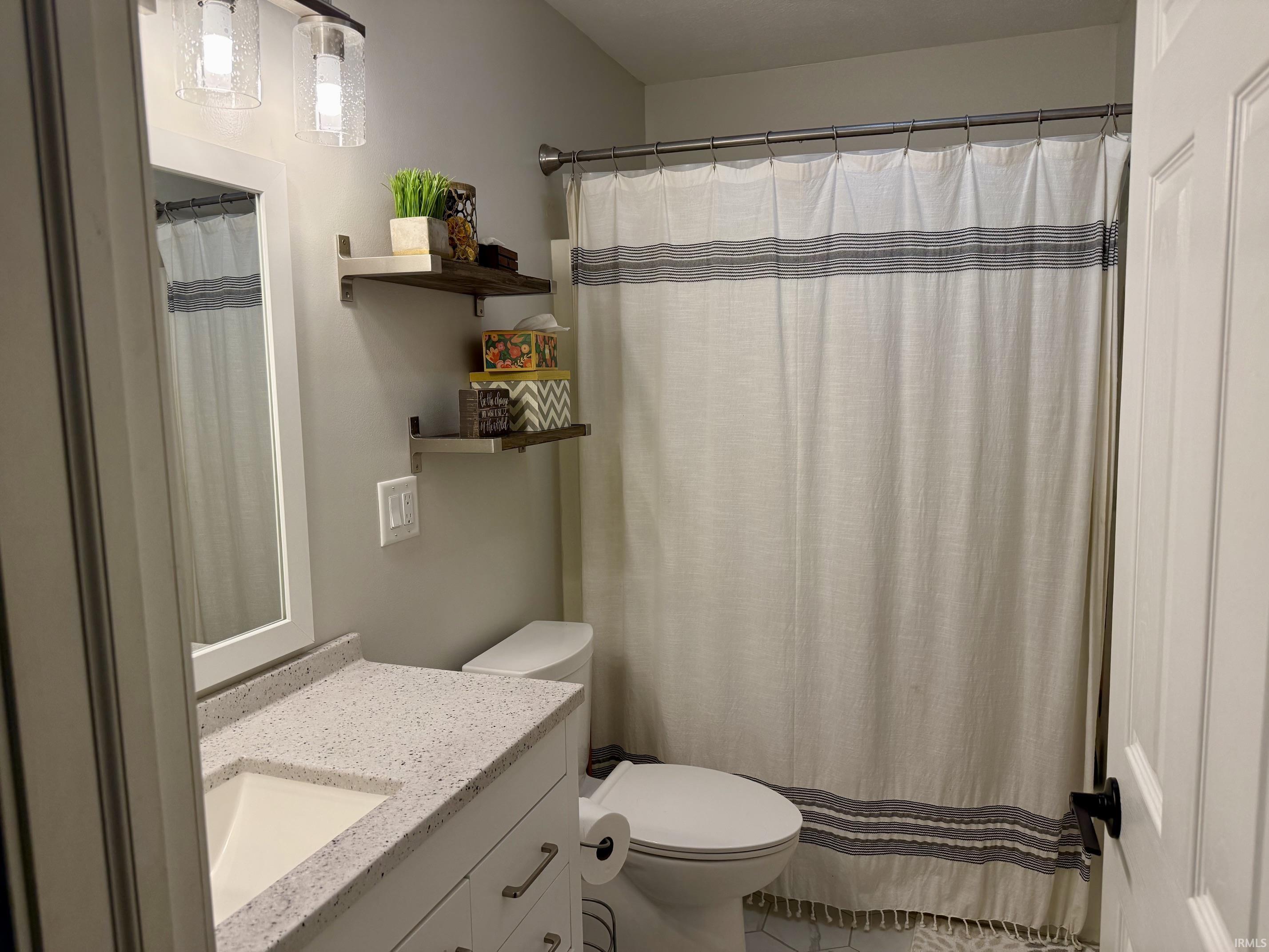 Modern bathroom featuring dual vanity with quartz countertop and integrated sink, chrome fixtures, and ample storage