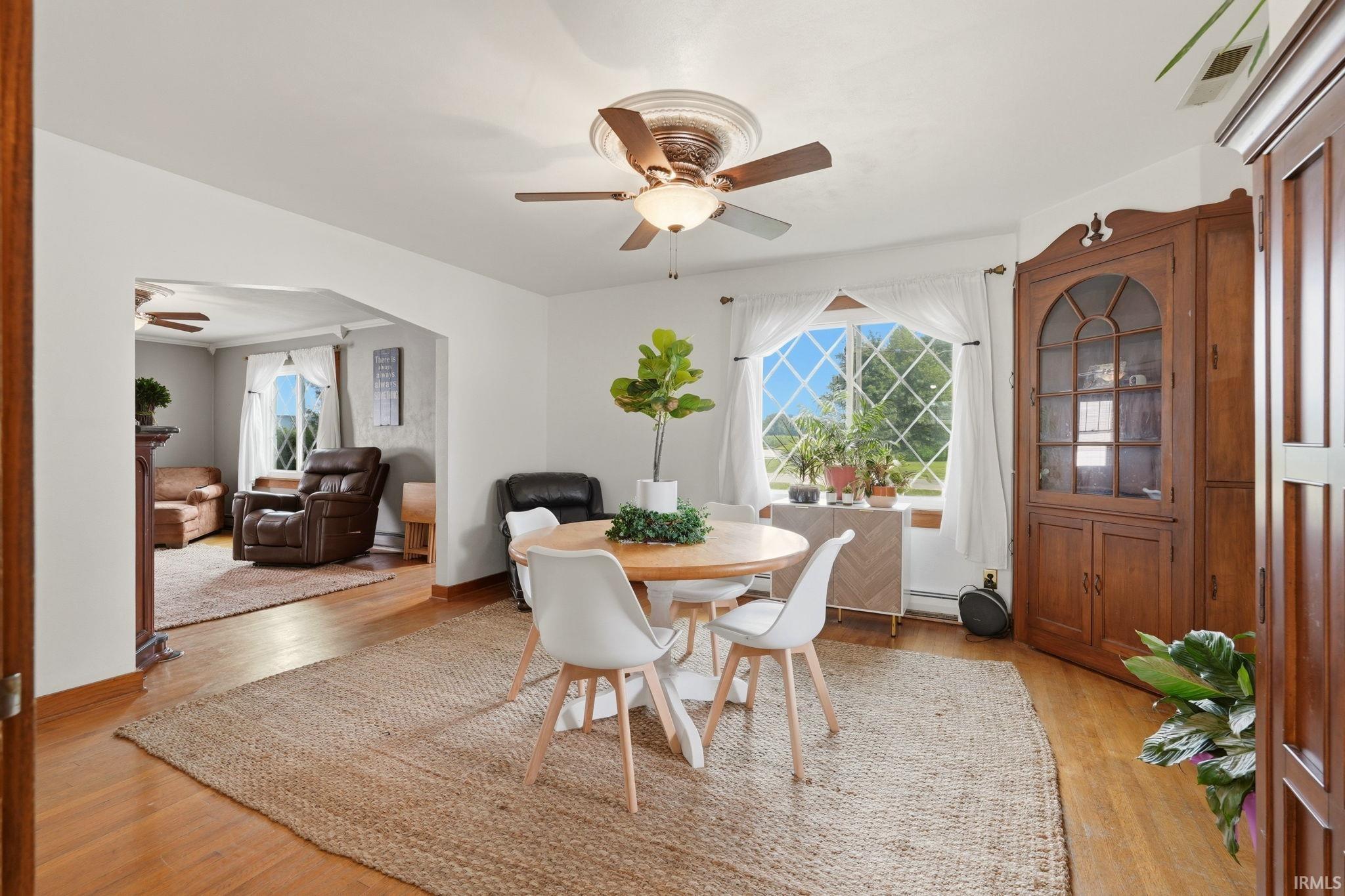 Bright dining area featuring hardwood flooring and an arched doorway