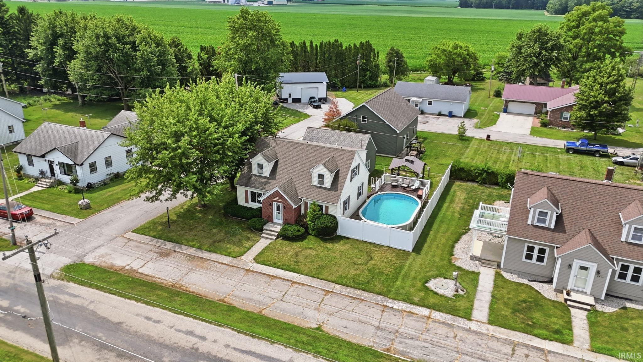 Traditional-style home featuring a brick facade and dormer windows, complemented by a white picket fence enclosing a backyard swimming pool