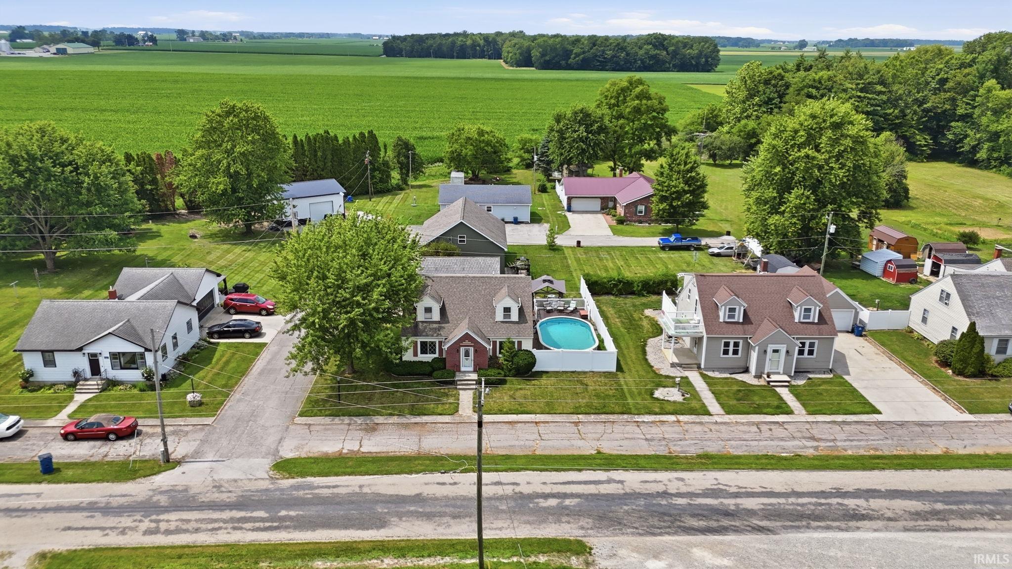 Cape Cod-style residence featuring dormer windows, a covered front entry, and a swimming pool within a fenced backyard