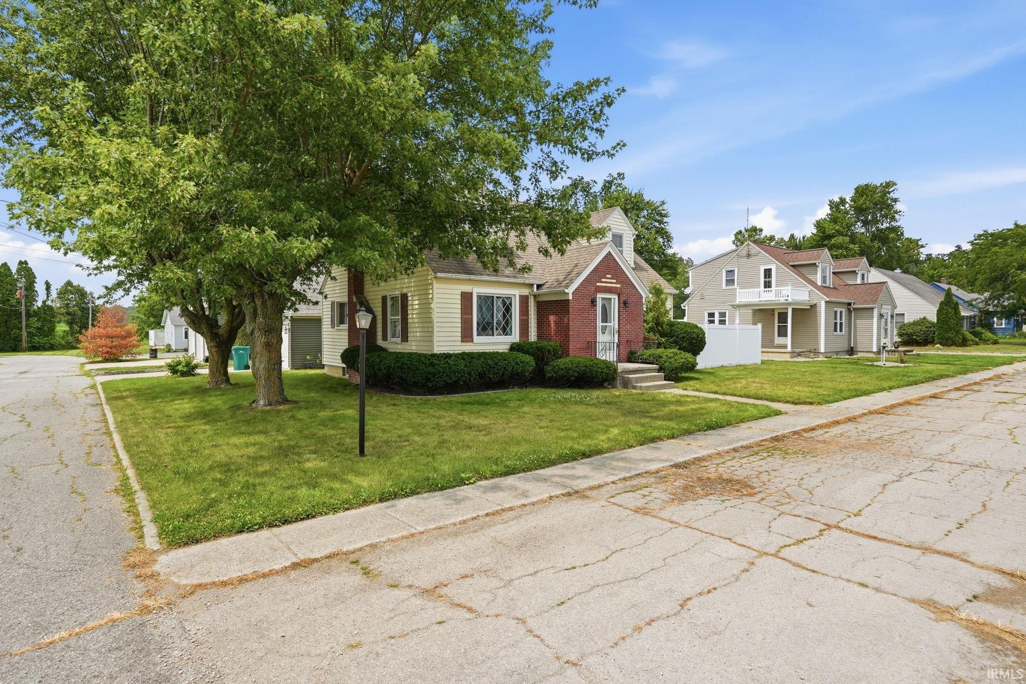 Traditional-style home featuring a light-colored siding exterior with dark red shutters and a brick accent facade