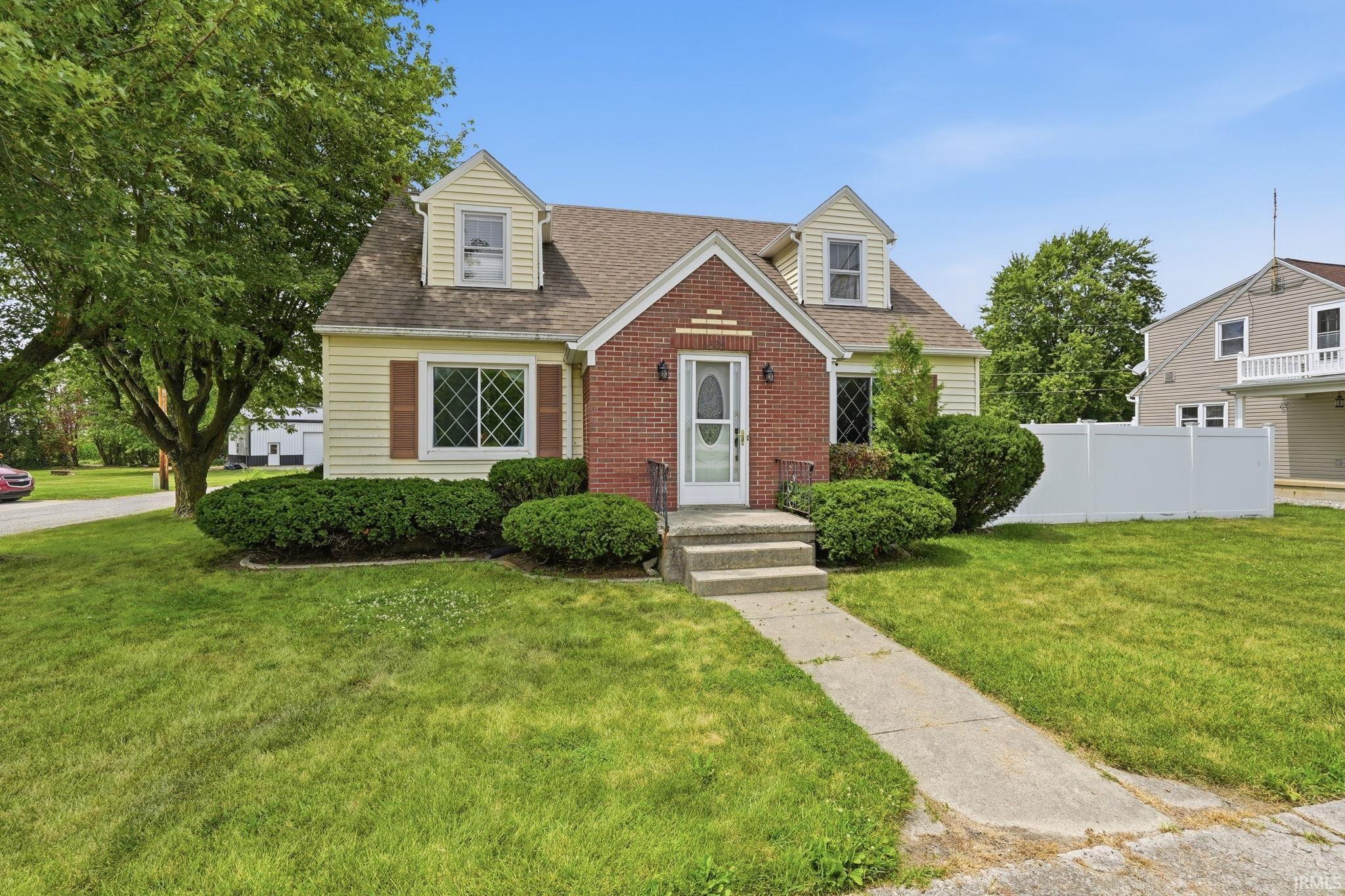 Cape Cod style exterior with yellow siding and red brick accents