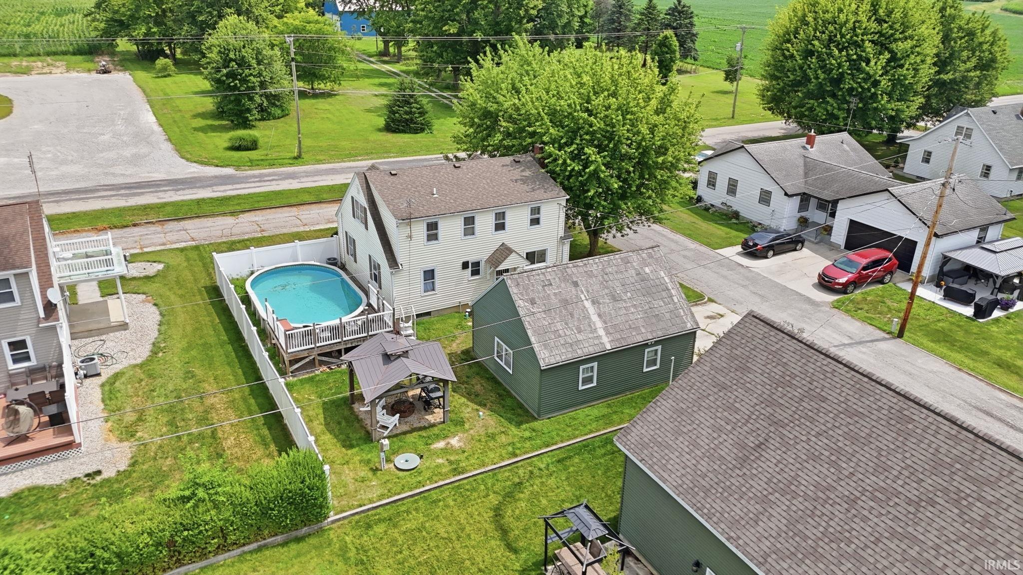 Backyard oasis featuring an above-ground swimming pool with surrounding deck, a dedicated outdoor gazebo area, and a white privacy fence