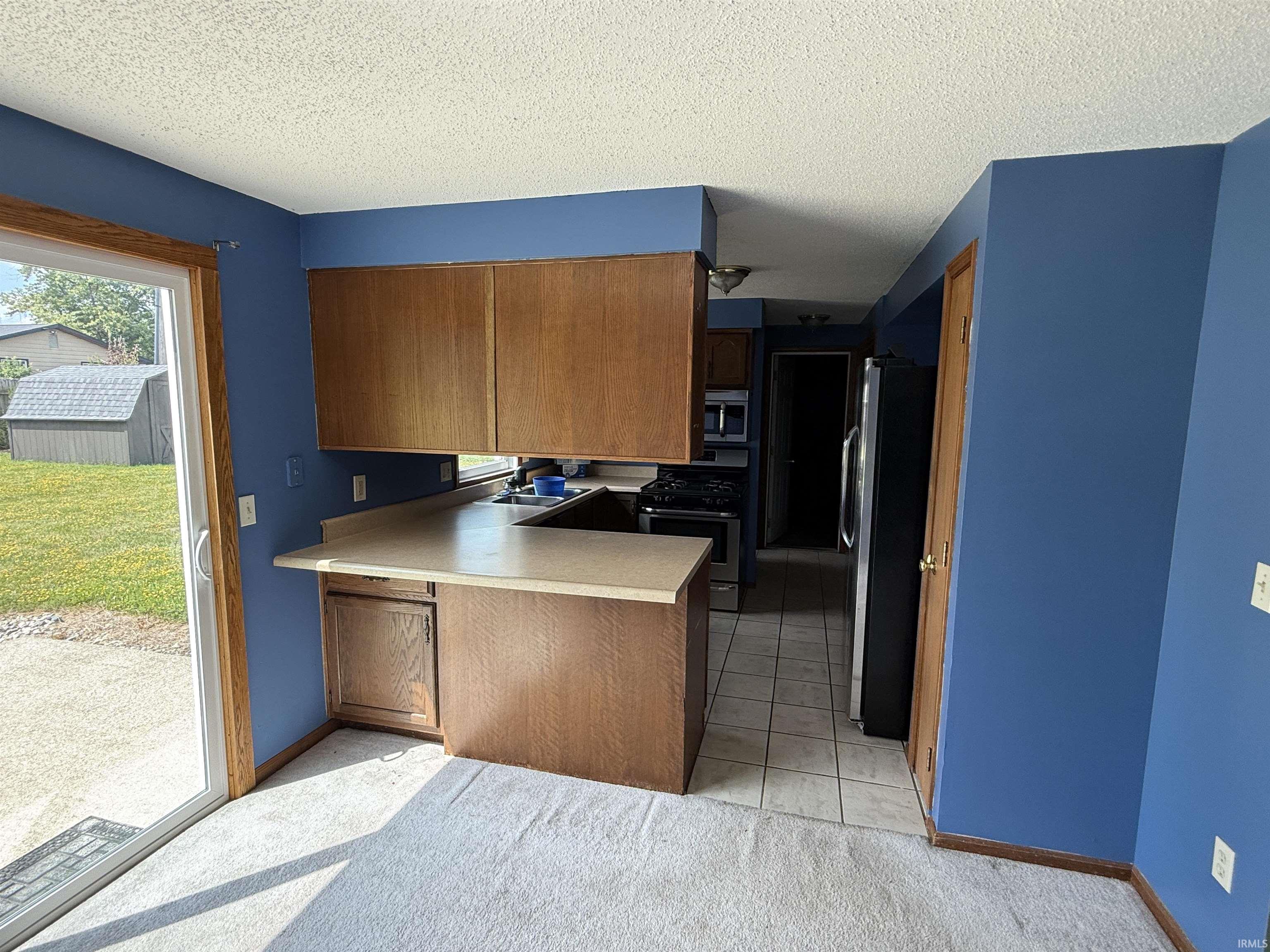Kitchen and dining area featuring wood-finish cabinetry, a built-in breakfast bar, and stainless steel appliances
