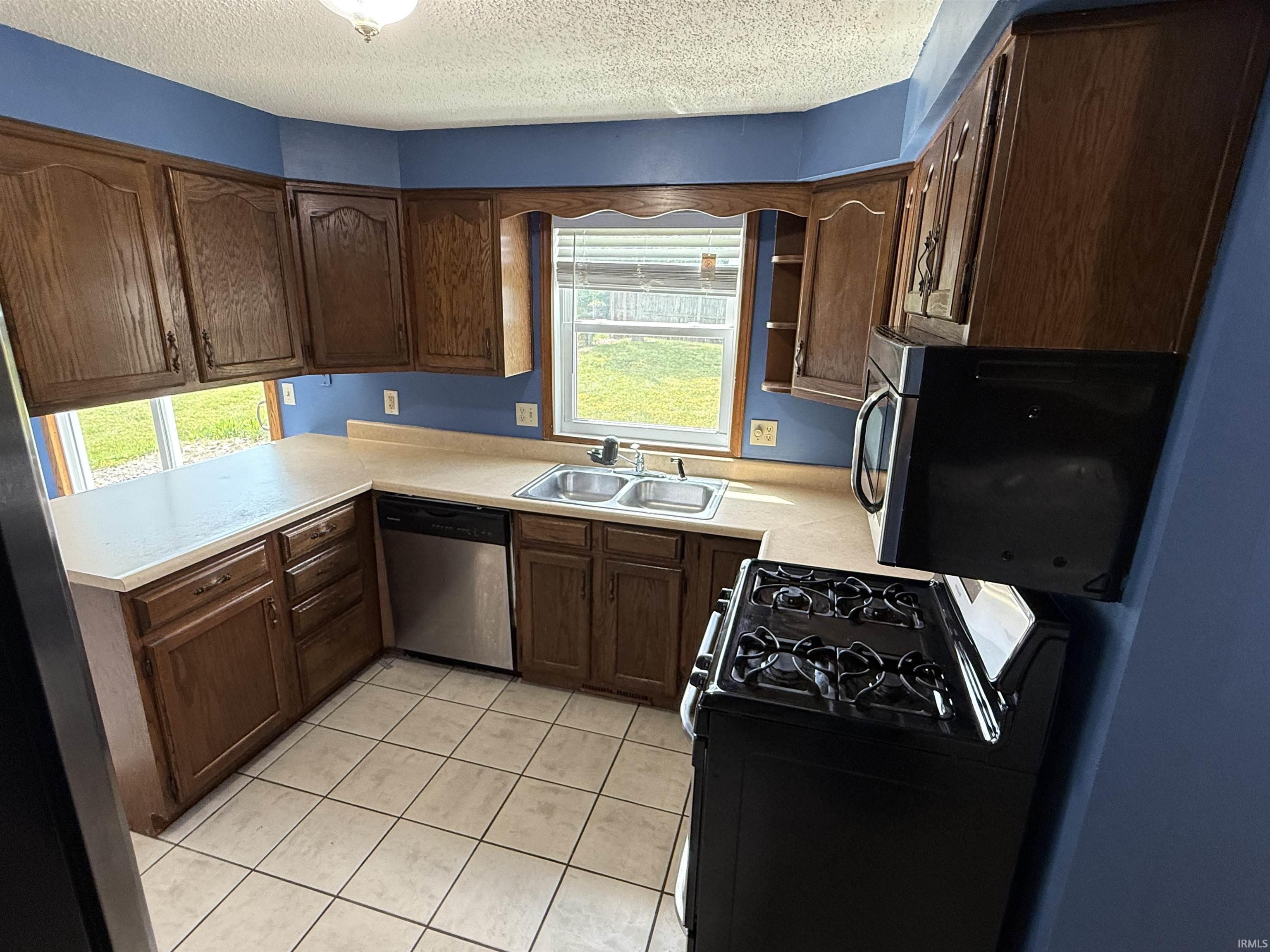 Kitchen featuring warm-toned wood cabinetry, neutral countertops, and tile flooring