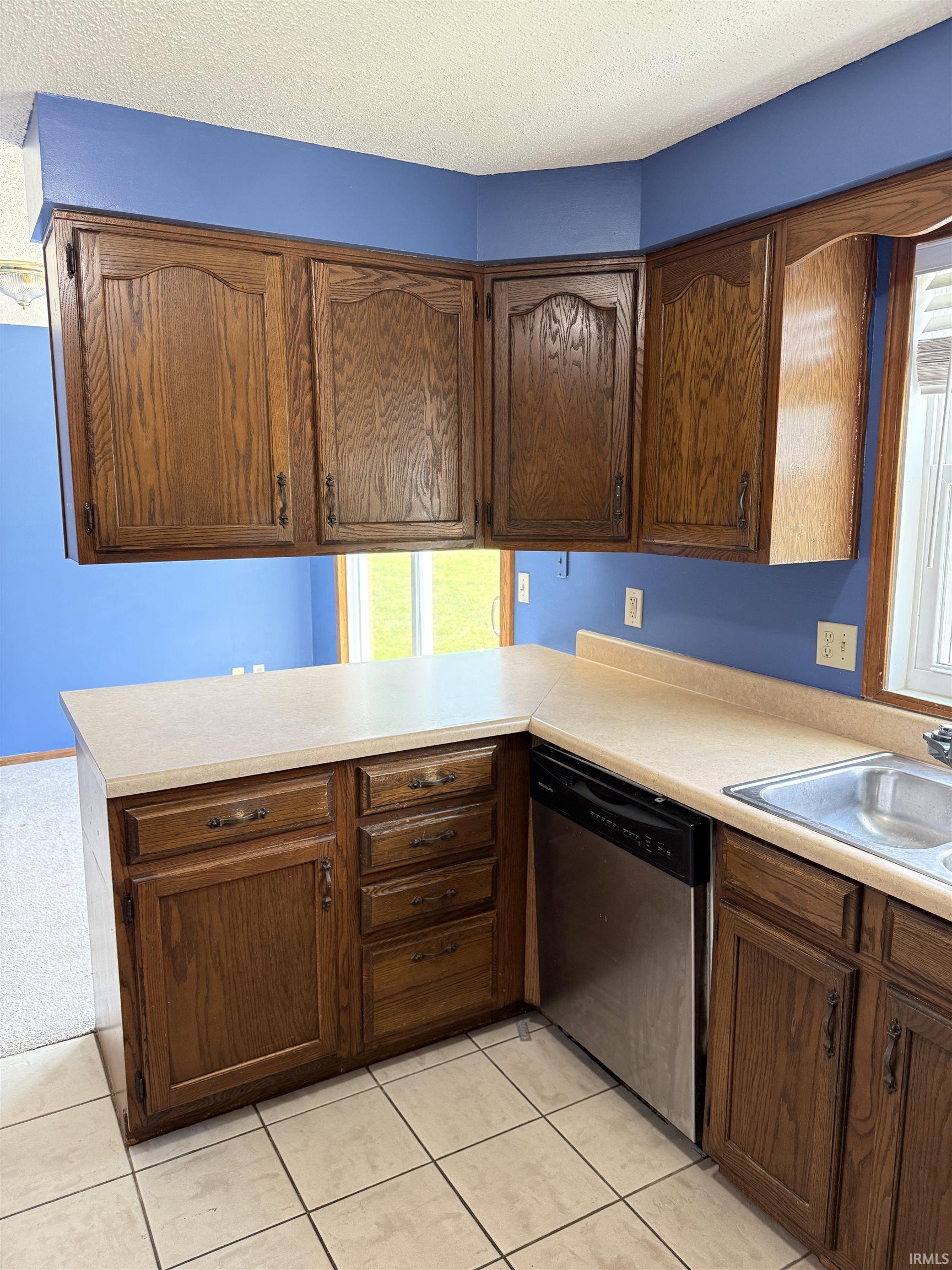 Kitchen featuring wood-finish cabinetry, neutral countertops, and tile flooring