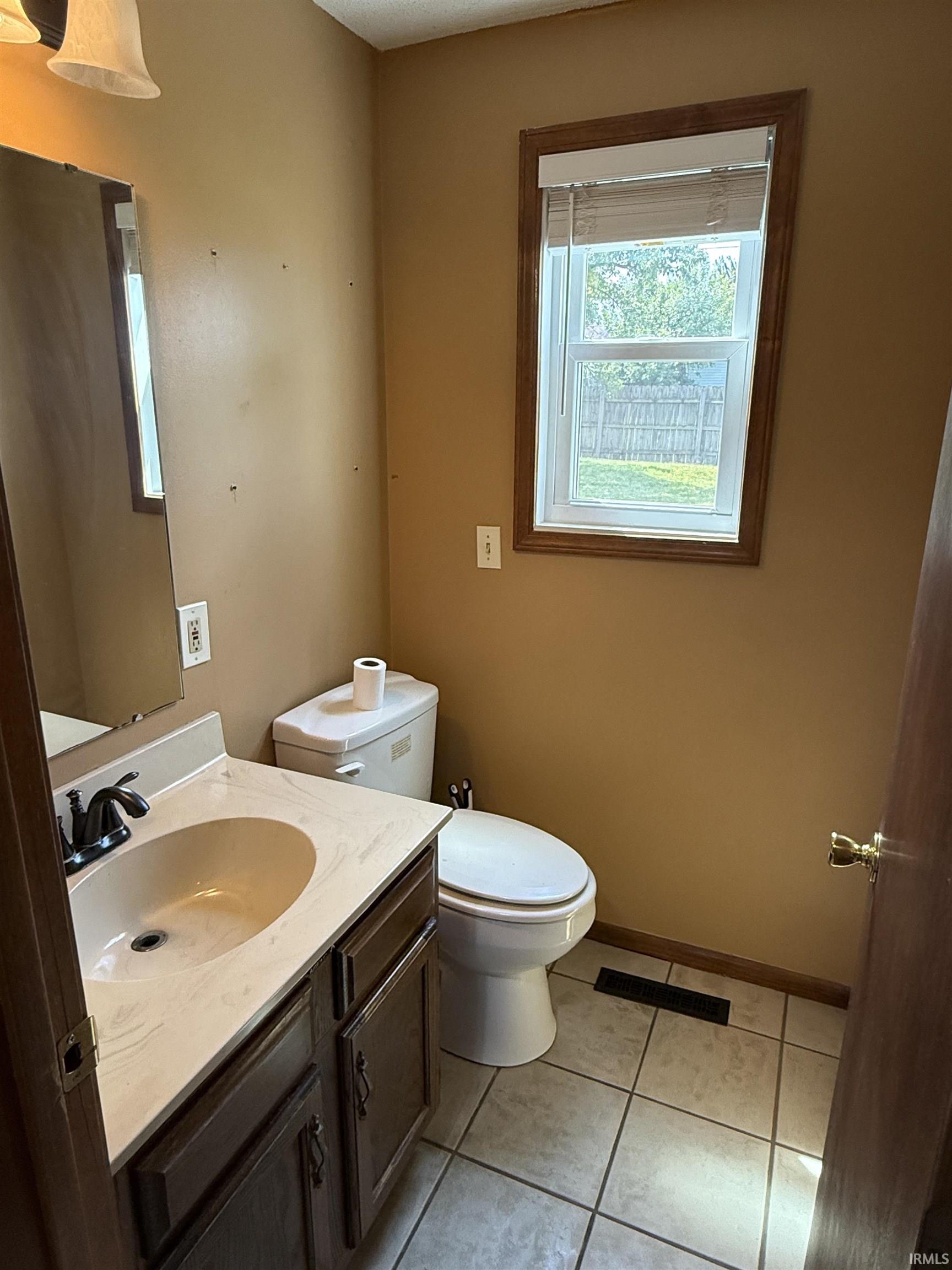 Bathroom featuring a white toilet, single vanity with a light-toned countertop, and dark wood-finish cabinetry