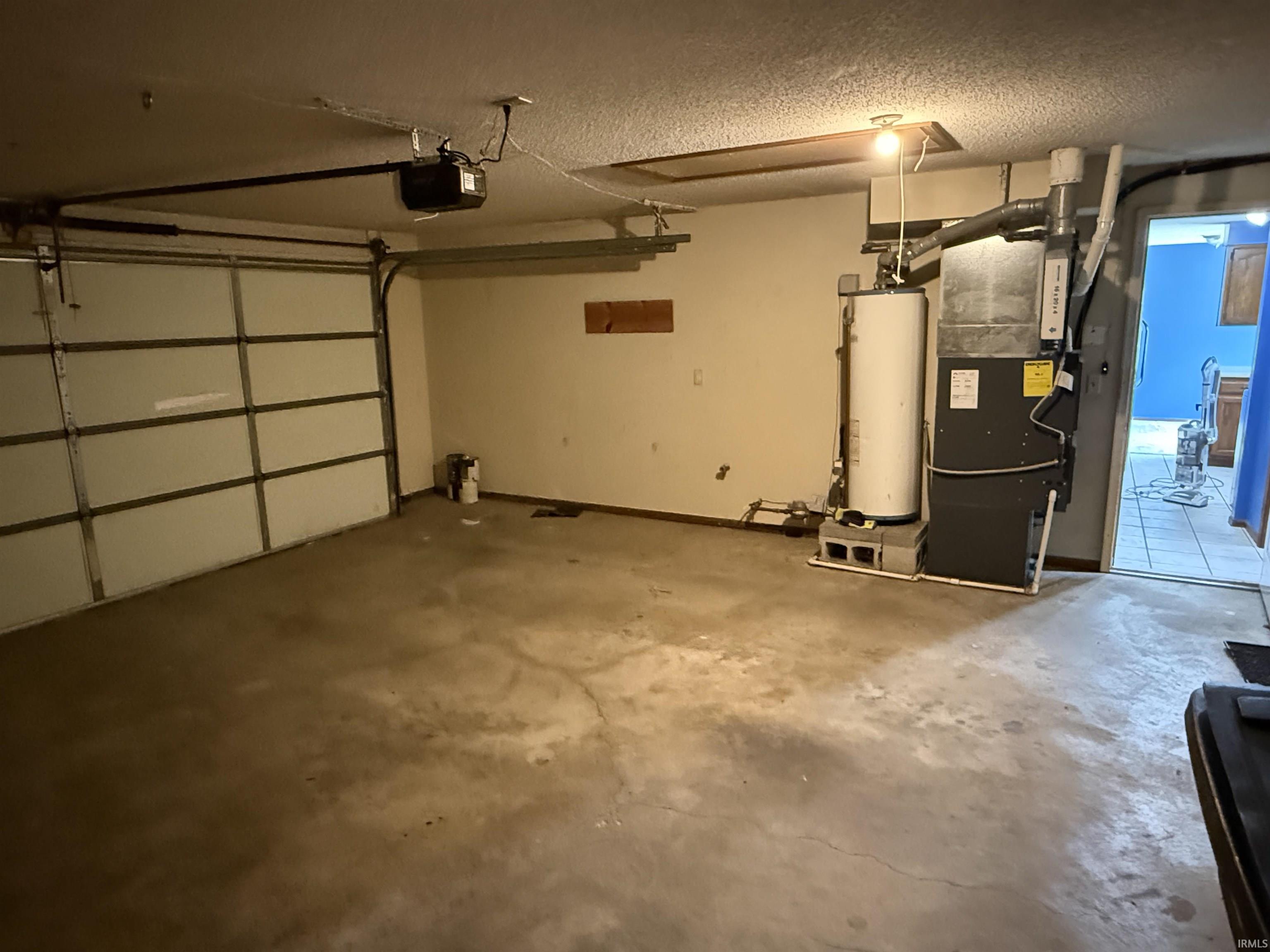Attached garage featuring a white sectional overhead door with an automatic opener, a water heater, and a furnace