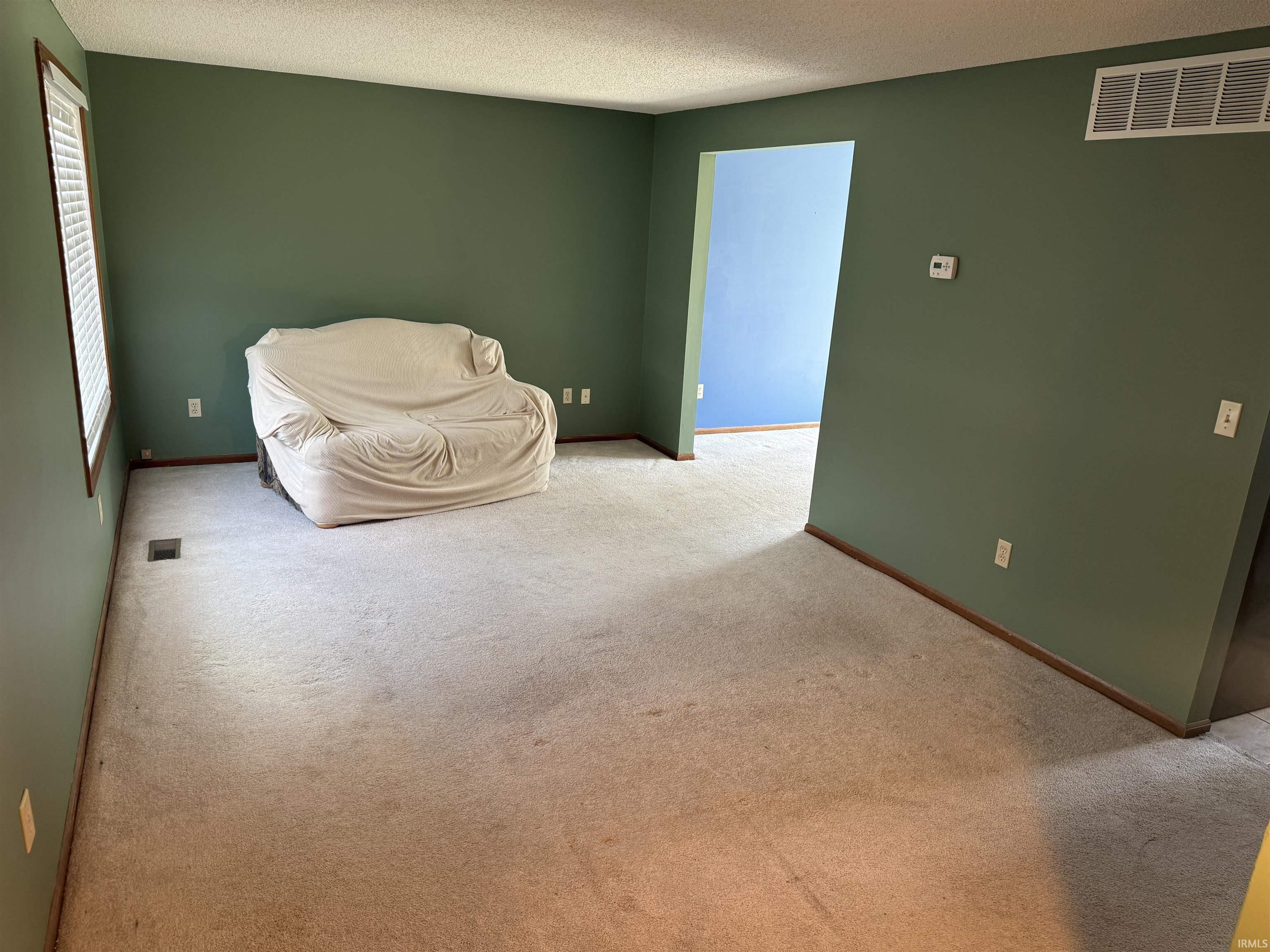Light-colored carpeting throughout, complemented by a window with white blinds and trim