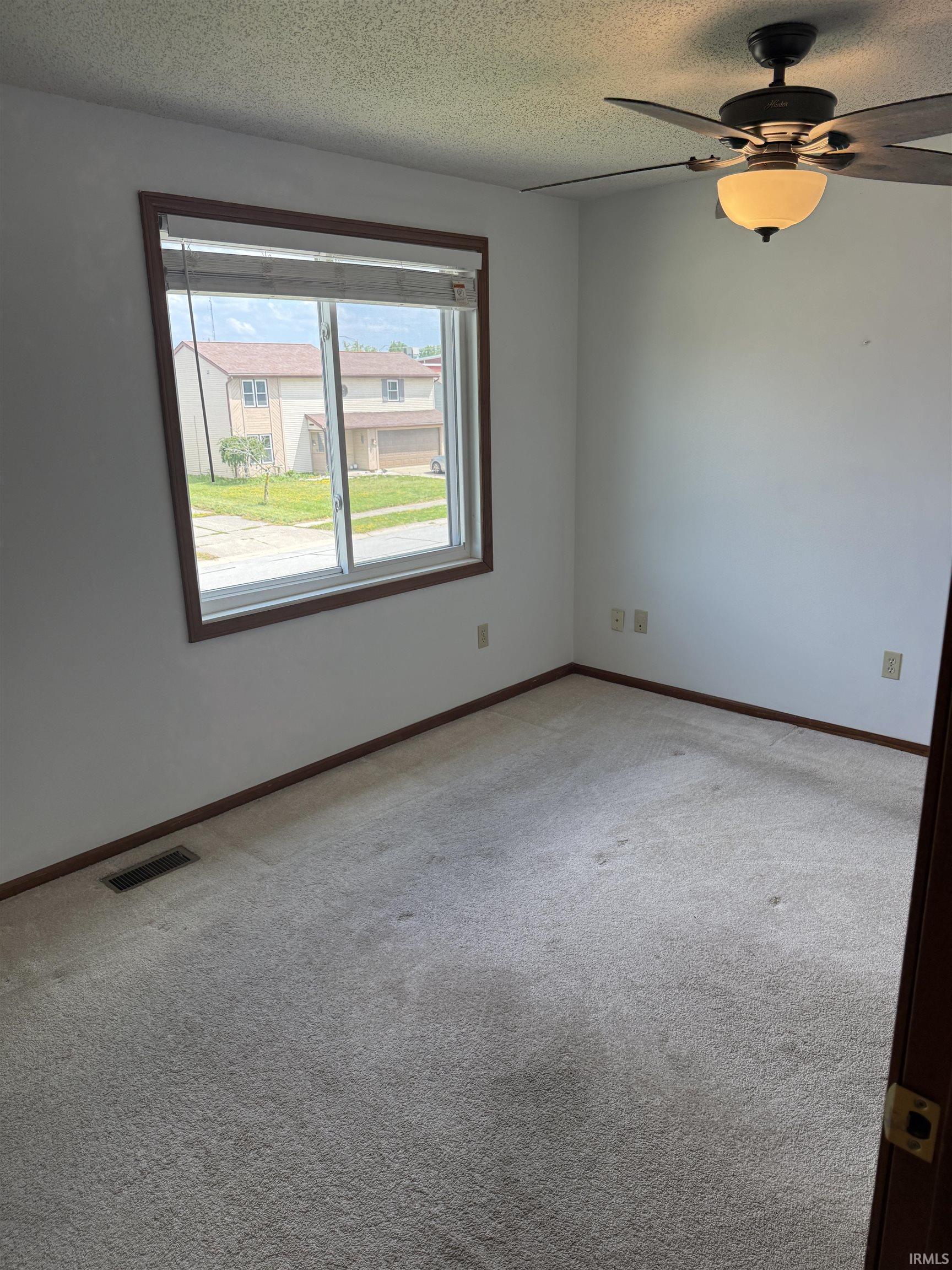 Carpeted room featuring a ceiling fan with integrated lighting, a double-paned window with wood trim, and baseboard trim