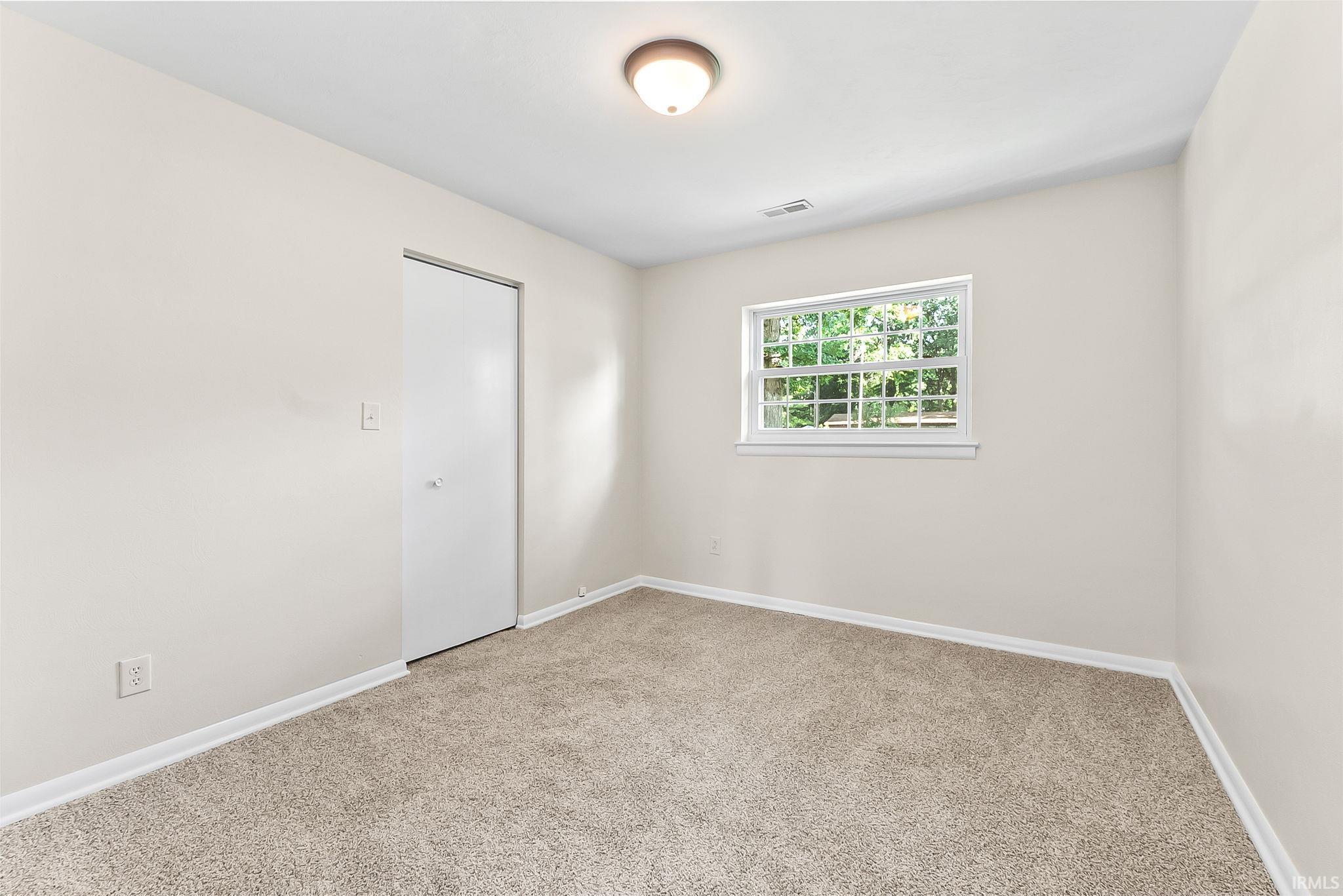 Neutral-toned walls, carpeted flooring, and a single window with grid panes
