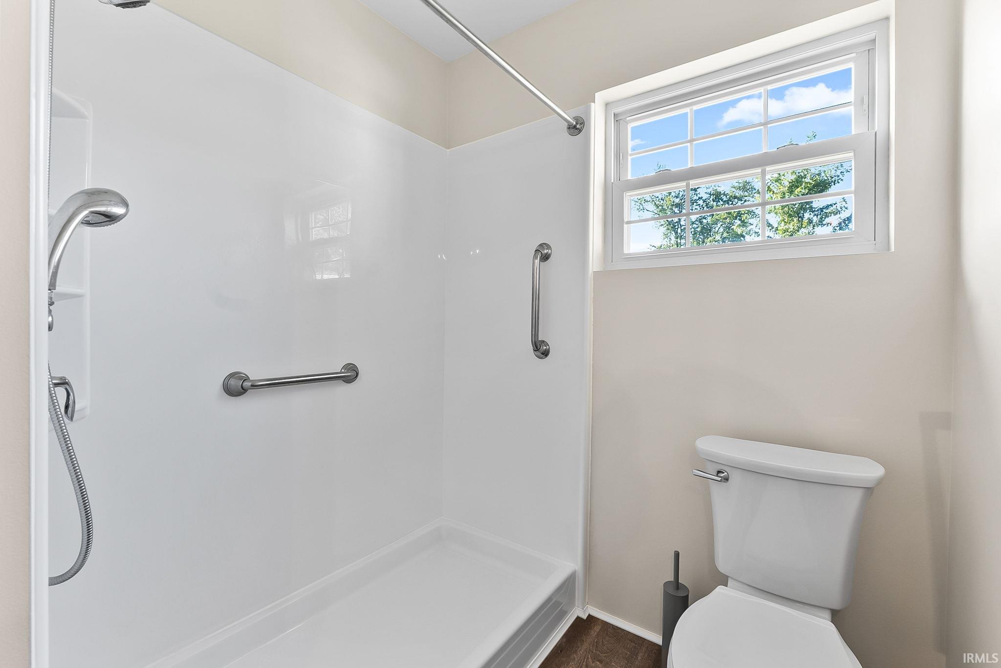 Modern bathroom featuring a spacious walk-in shower with frameless glass enclosure, dual showerheads, and grab bars
