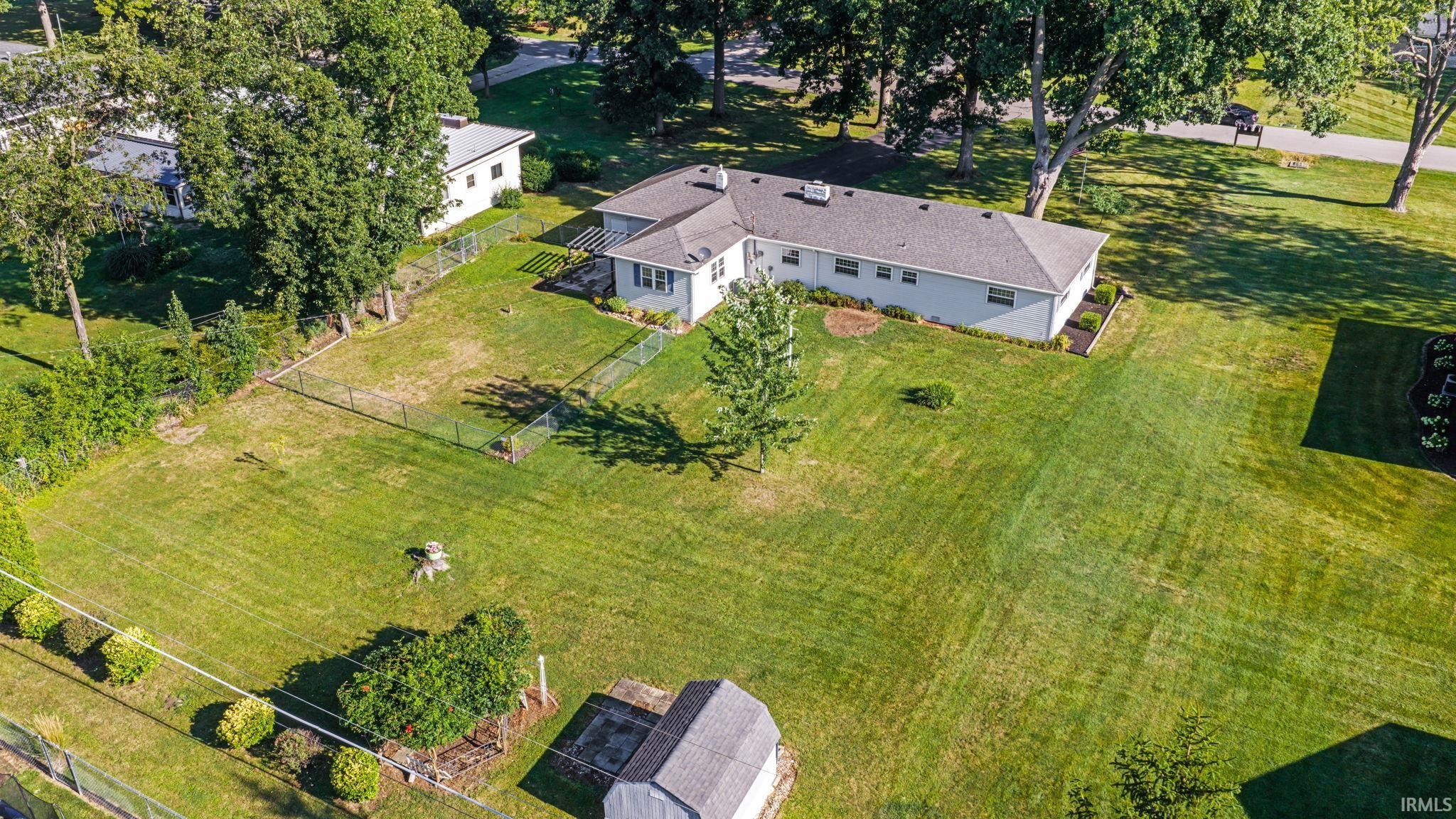 Expansive property featuring a single-story residence with a gabled roof and light-colored siding