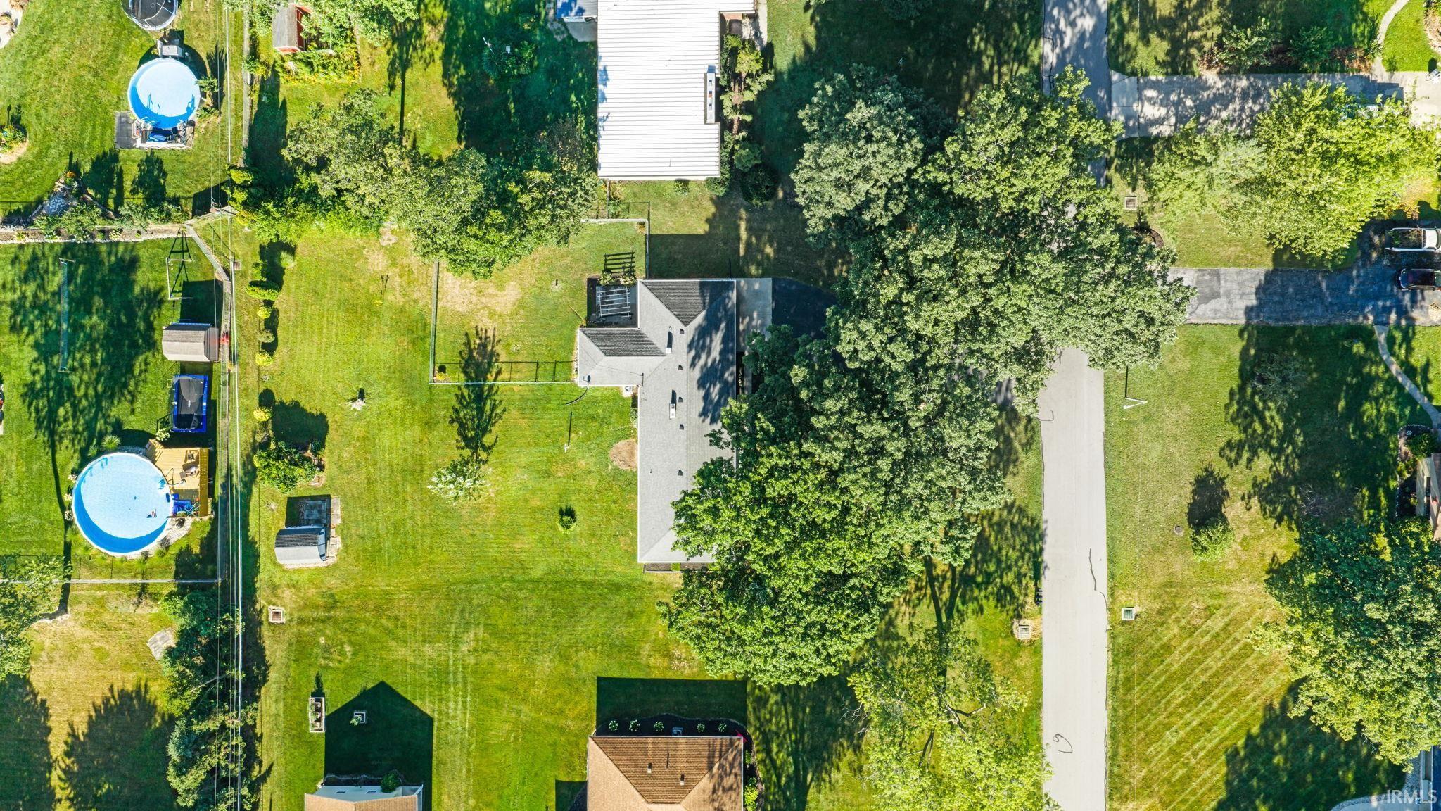 Expansive property featuring mature trees and a substantial paved driveway