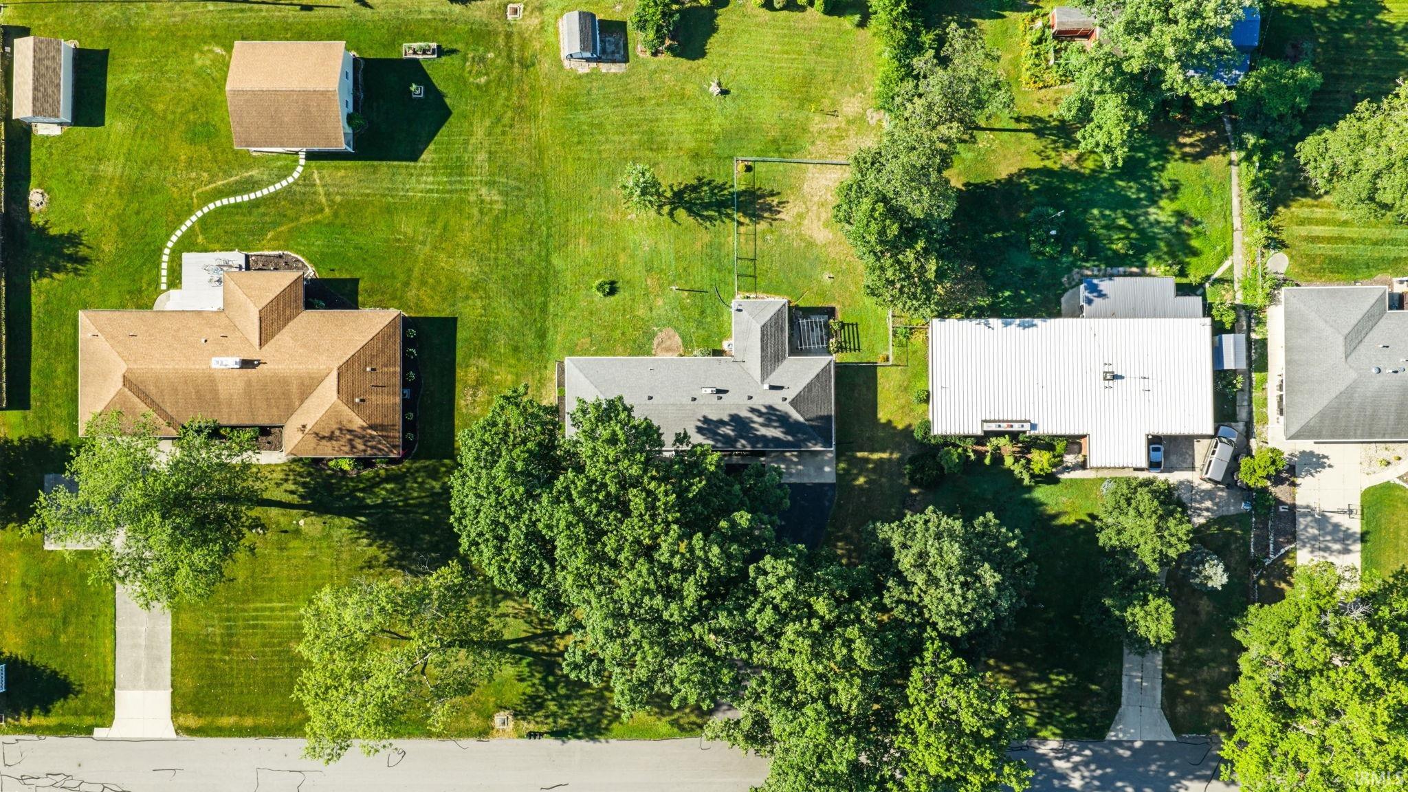 Expansive lot featuring mature trees, a driveway, and a well-maintained lawn