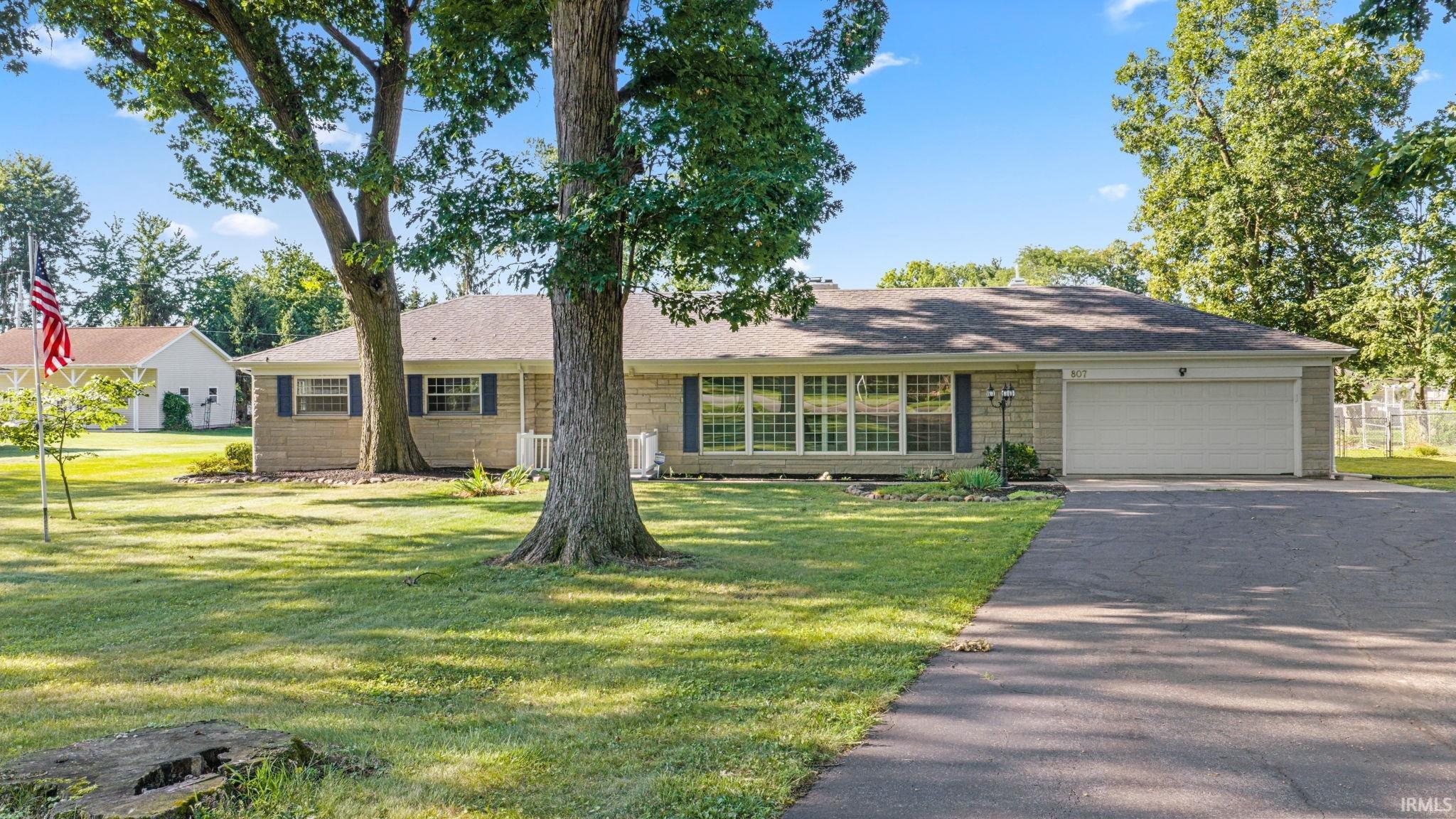 Brick exterior with blue shutters, a paved driveway, and an attached garage