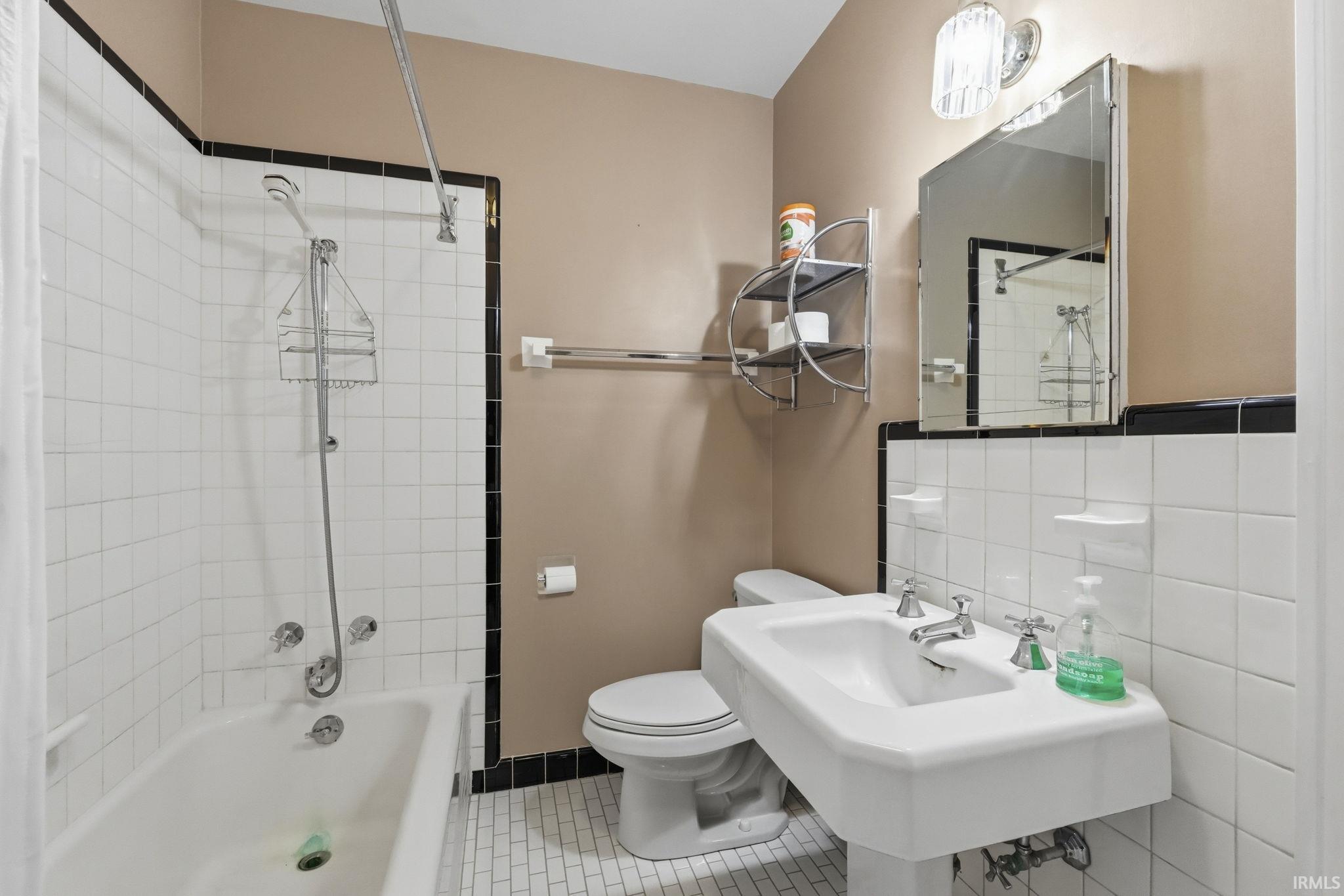 Clean, contemporary bathroom featuring a frameless glass-enclosed shower with subway tile surround, dual-sink vanity with white porcelain basin and chrome fixtures, white subway tile wainscoting, and a toilet with chrome trim