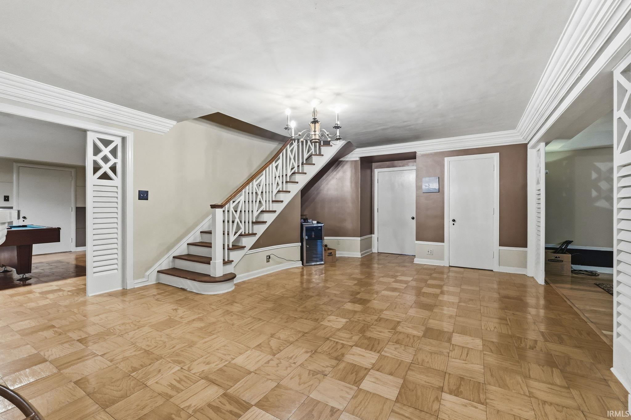 Spacious foyer featuring a striking staircase with decorative spindle railings and an elegant chandelier