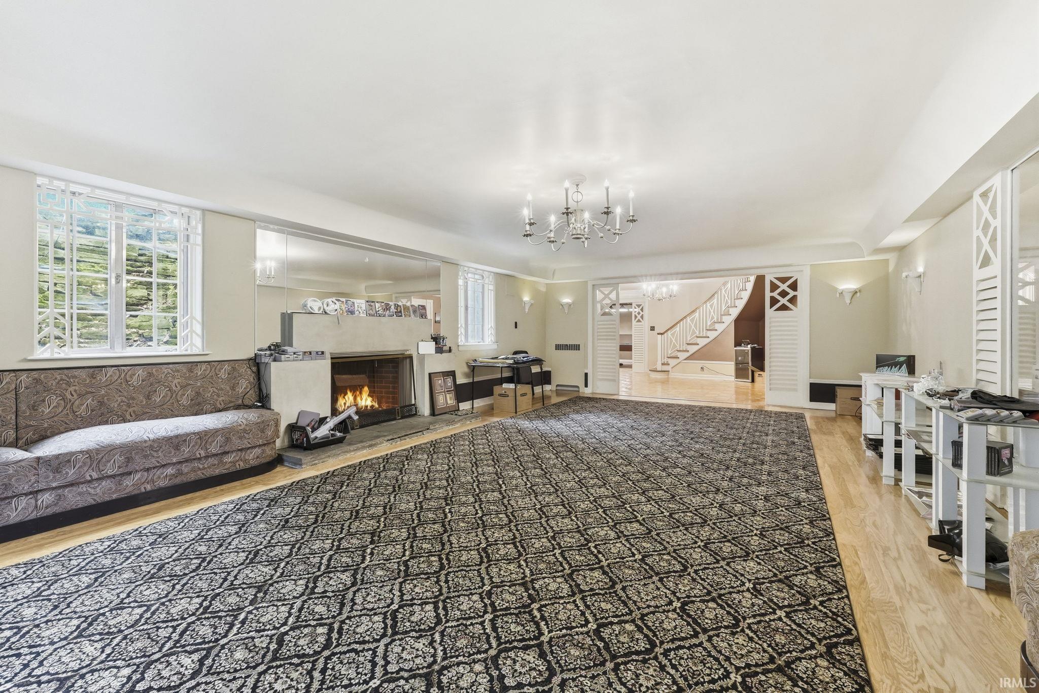 Spacious living area featuring a fireplace, chandelier lighting, and hard-surface flooring