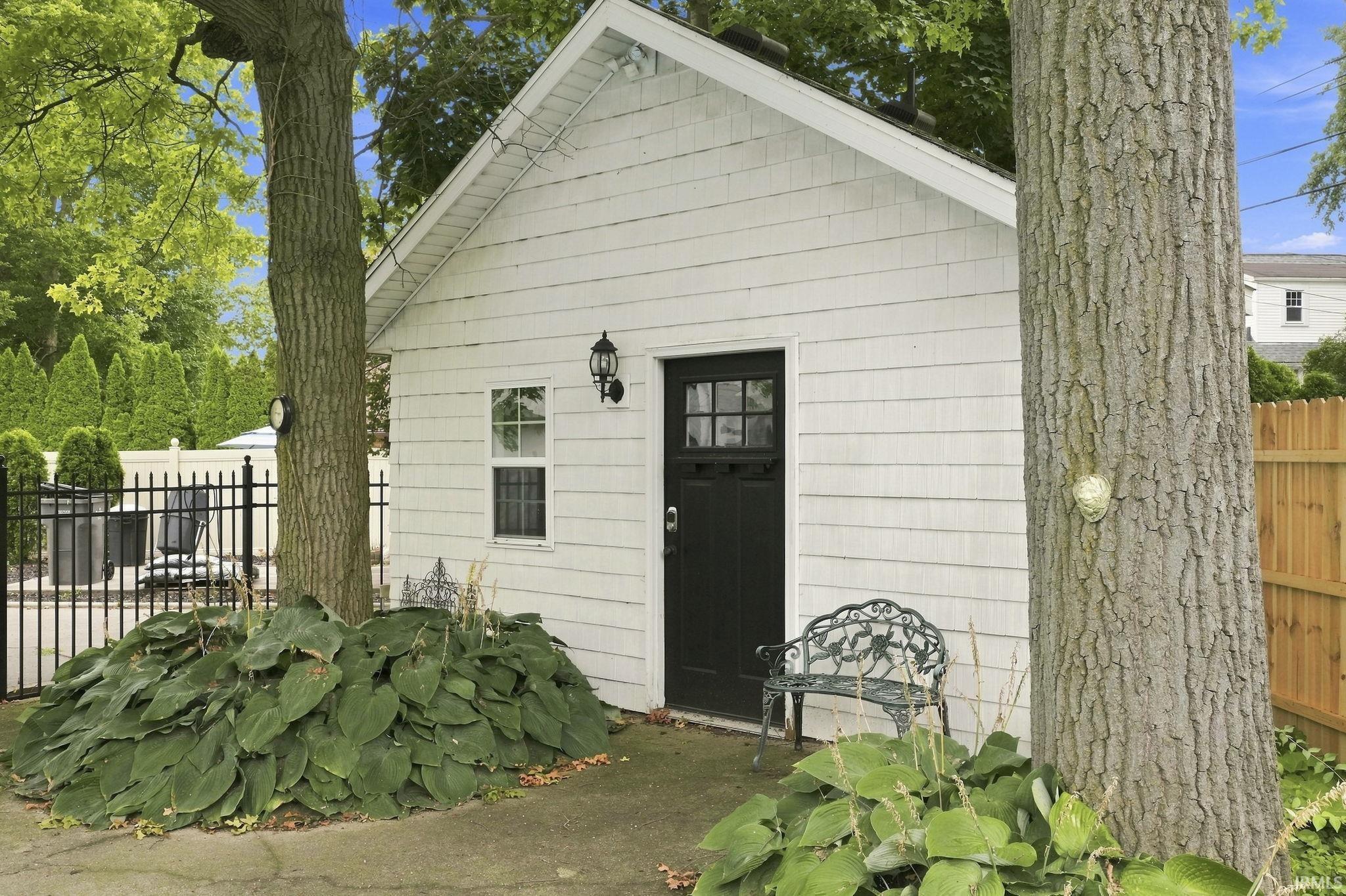 Charming cottage featuring white horizontal siding, black entry door with transom window, and casement windows