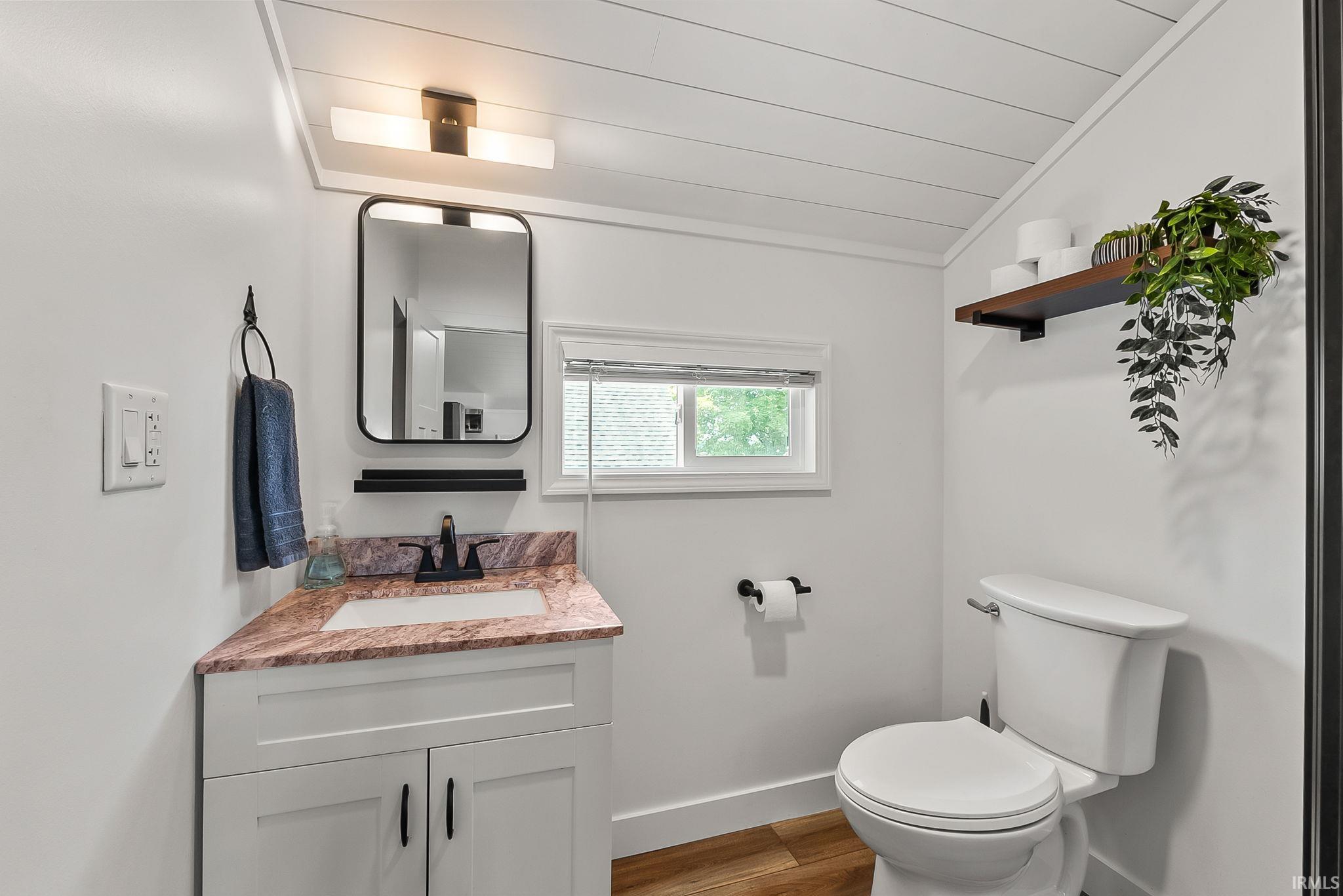 Modern bathroom featuring a gray vanity with a wood-finish countertop, vessel sink, and matte black faucet