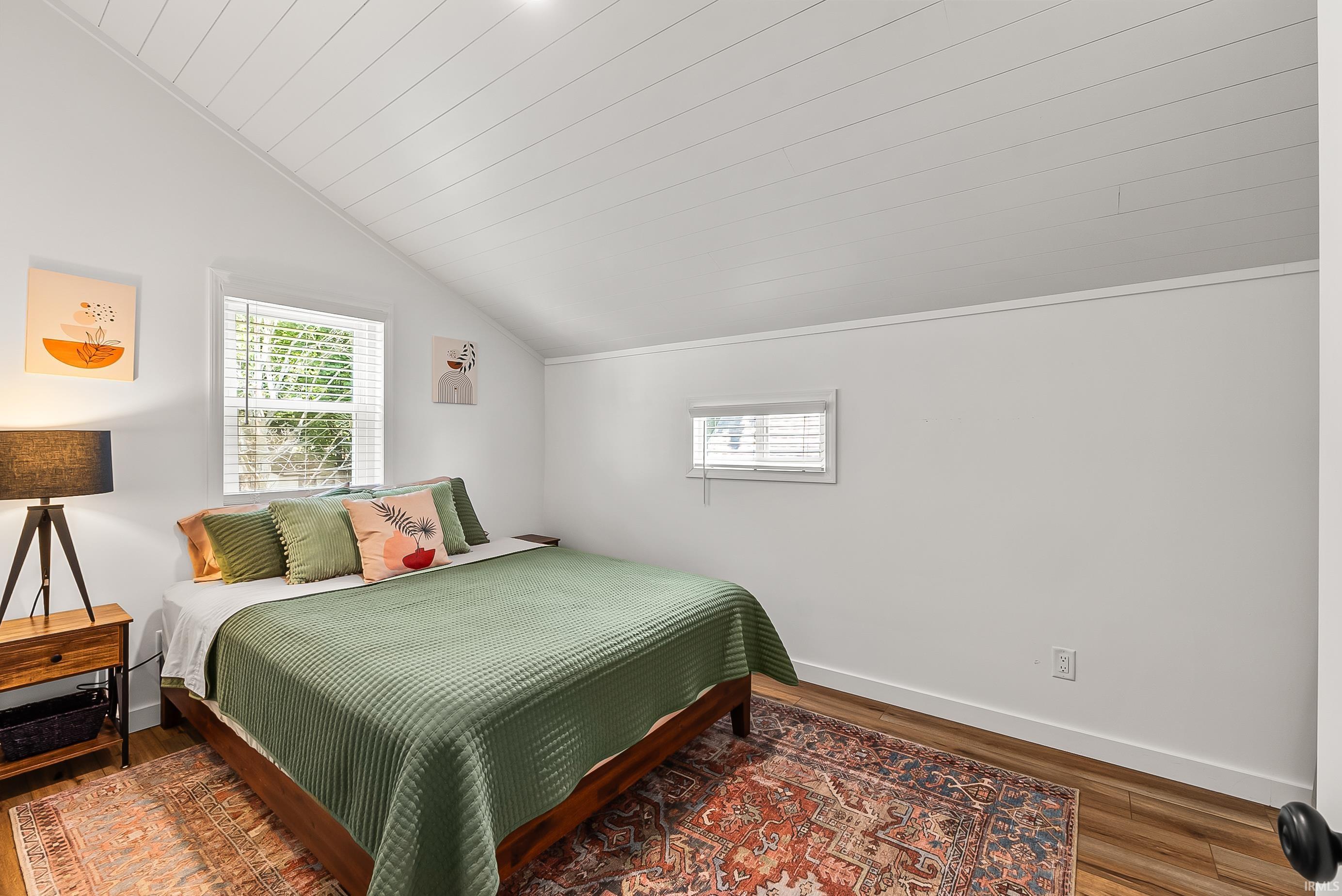 Sloped ceiling with shiplap finish, wood-finish flooring, and white painted walls