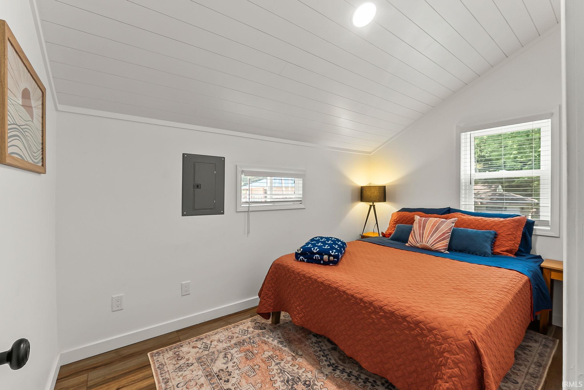 Bright bedroom featuring wood-finish flooring, white shiplap ceiling with recessed lighting, and dual windows providing natural light