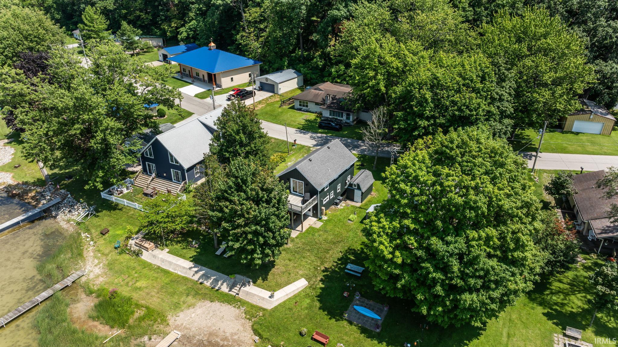 Waterfront property featuring a private dock, expansive green space, and mature trees