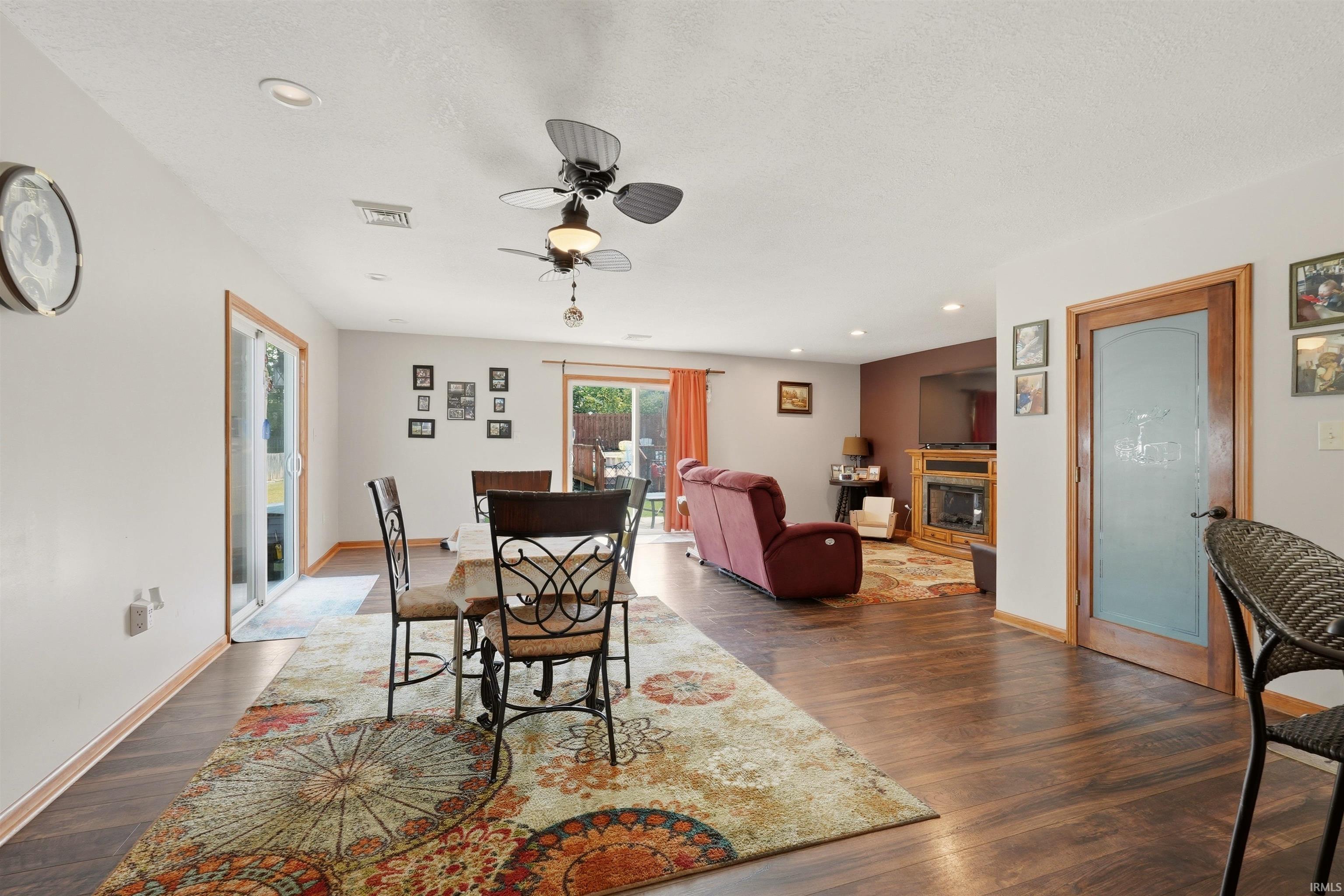 Open concept living area featuring wood-finish flooring, recessed lighting, and a fireplace with a wood mantle