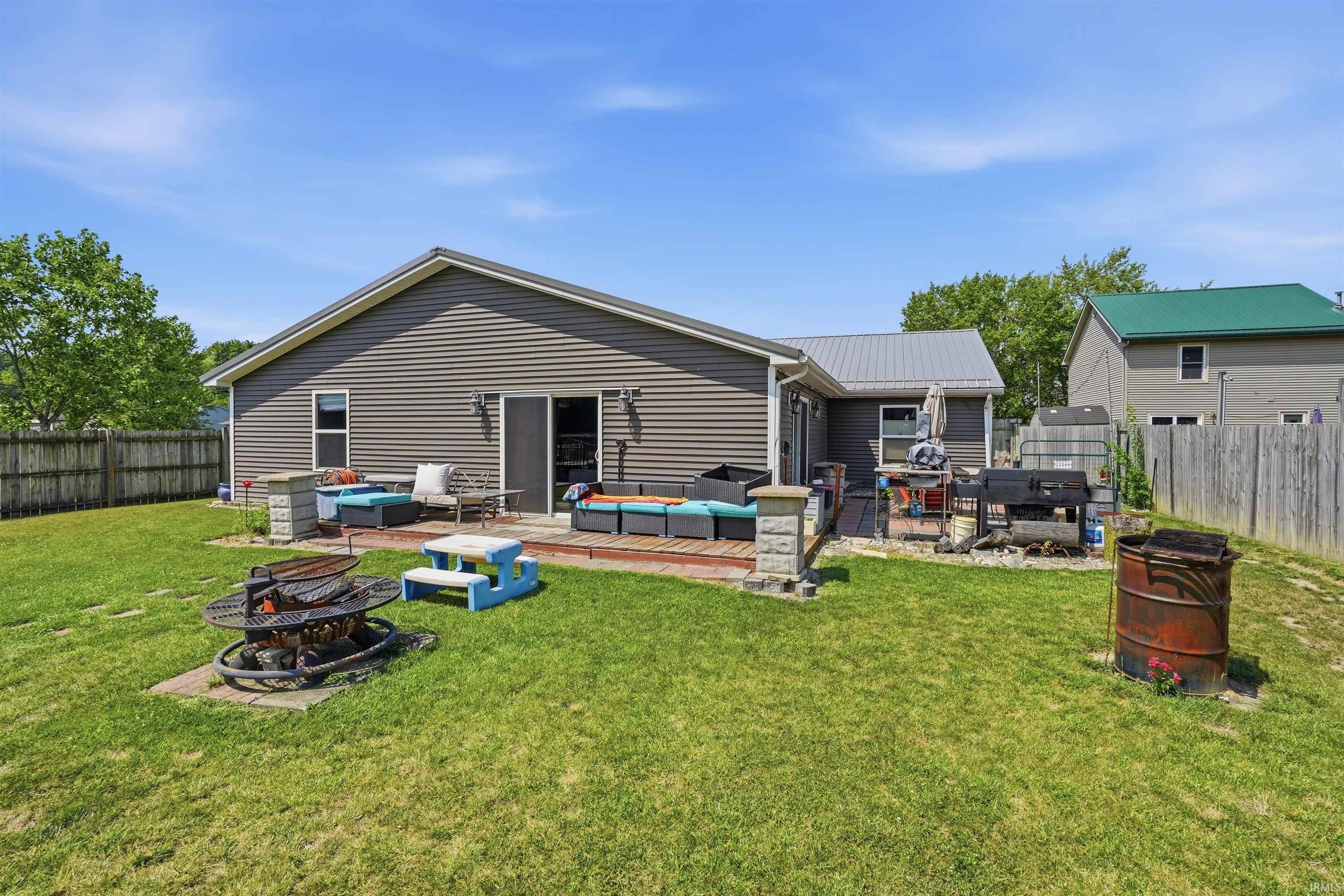 Expansive backyard featuring a wood deck, sliding glass door, and a permanent fire pit