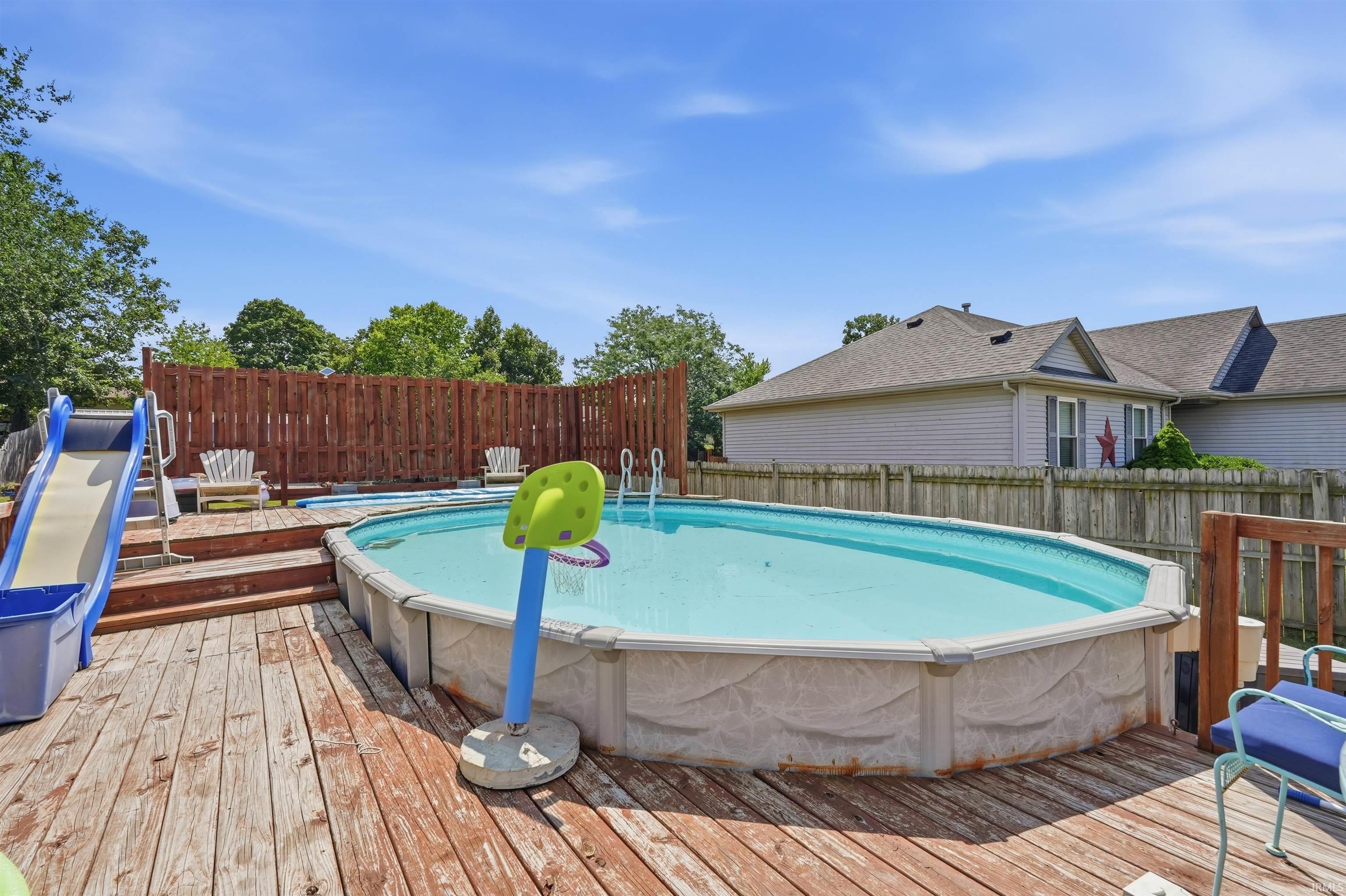 Expansive wood deck with an above-ground pool and wood privacy fencing