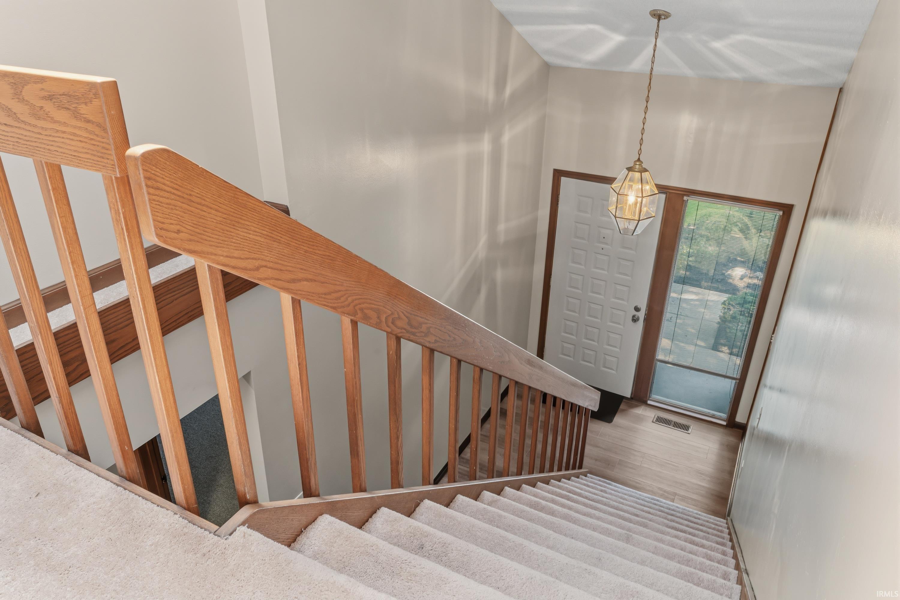 Foyer featuring light wood-finish flooring, a decorative glass paneled entry door, and a multi-paned sidelight