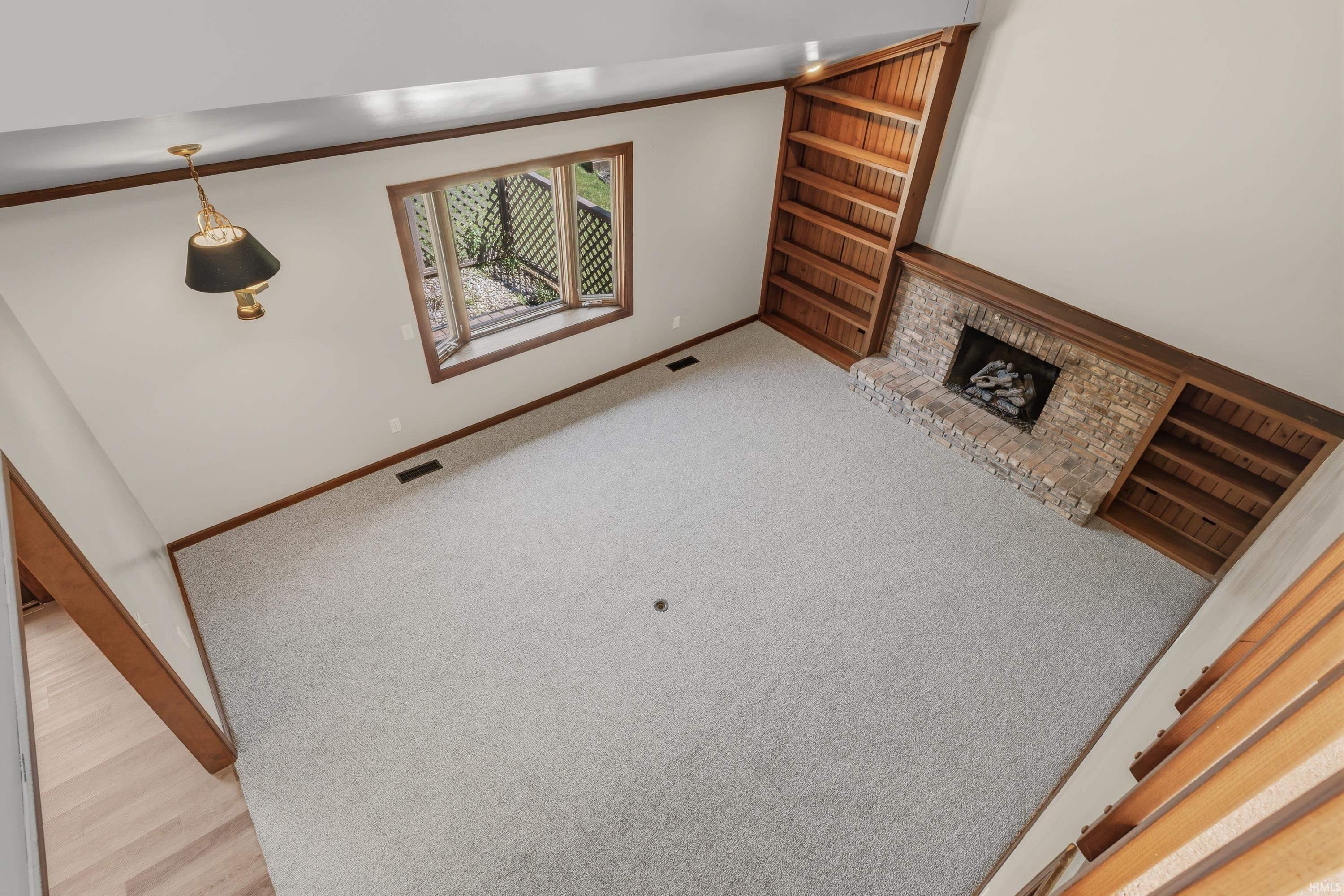 Spacious upper-level room featuring neutral carpet flooring, wood-trimmed architectural details, and abundant natural light from a multi-pane window