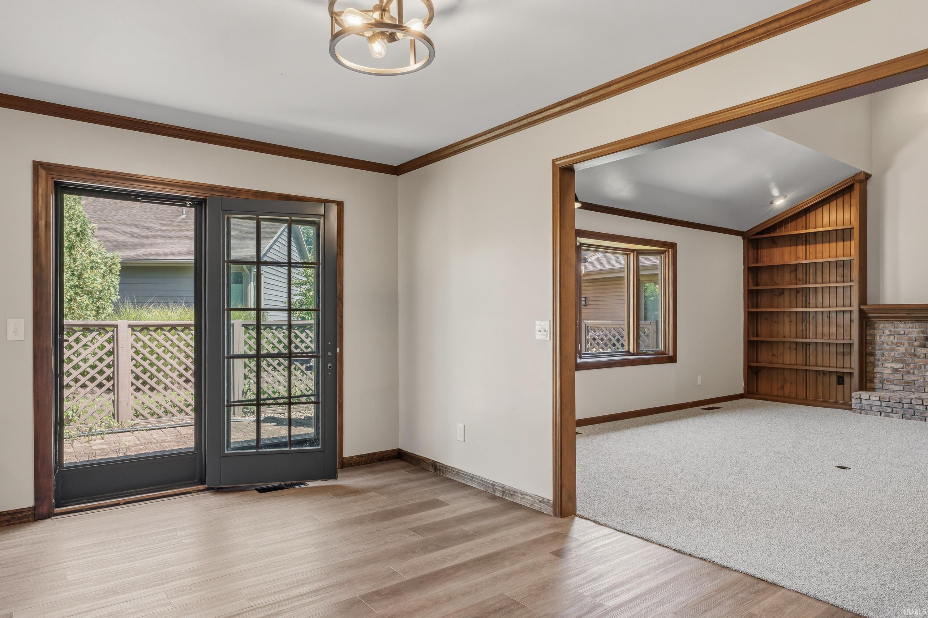 Wood-finish flooring, accent trim, ceiling light fixture, and double glass-paneled doors leading to a private deck