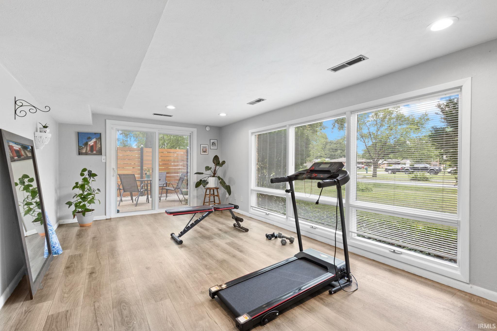 Recessed lighting, wood-finish flooring, sliding glass door, white trim, and a large window wall