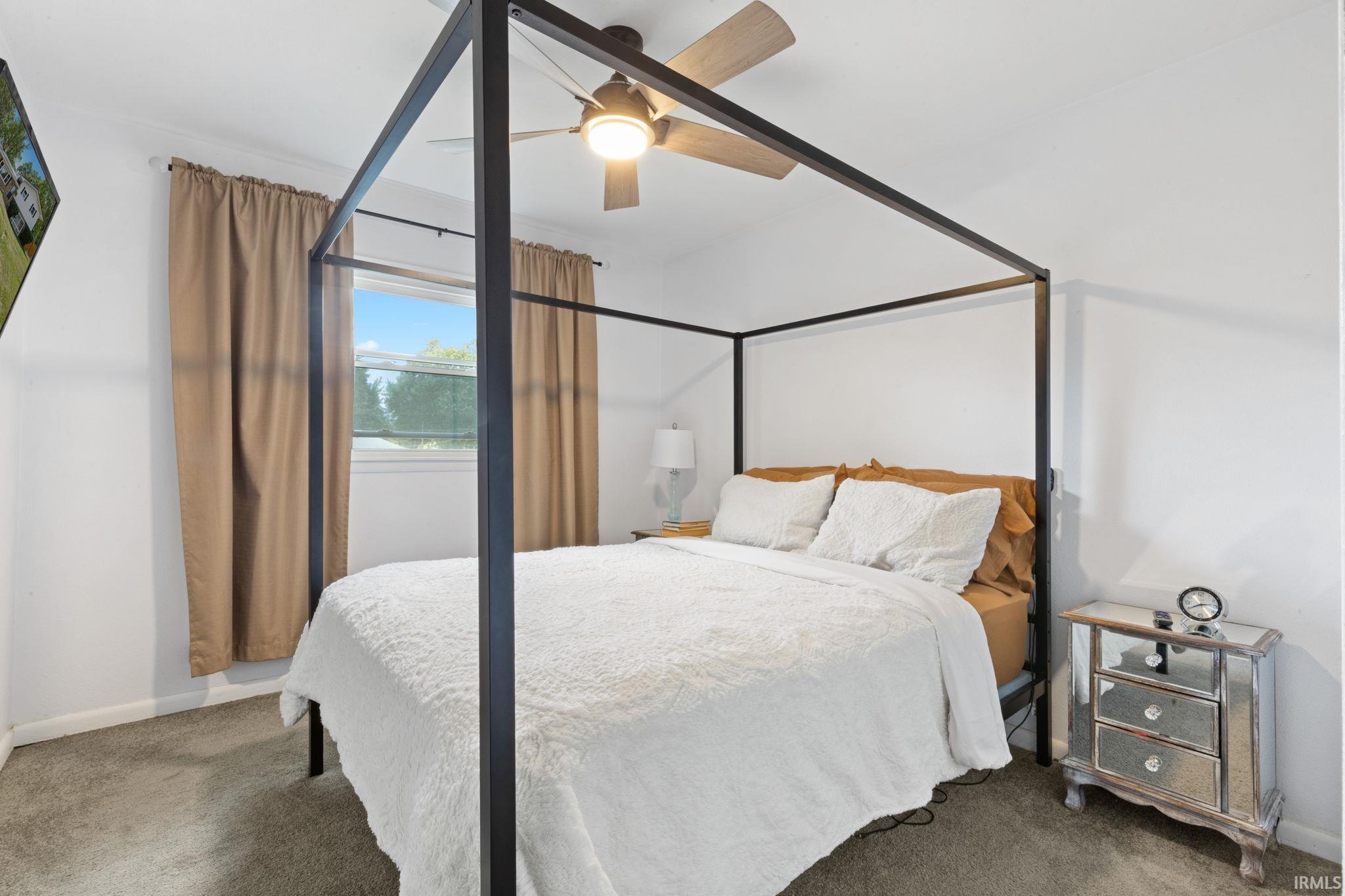 Carpeted flooring with white wall finishes, a ceiling fan with integrated lighting, and a window providing natural light