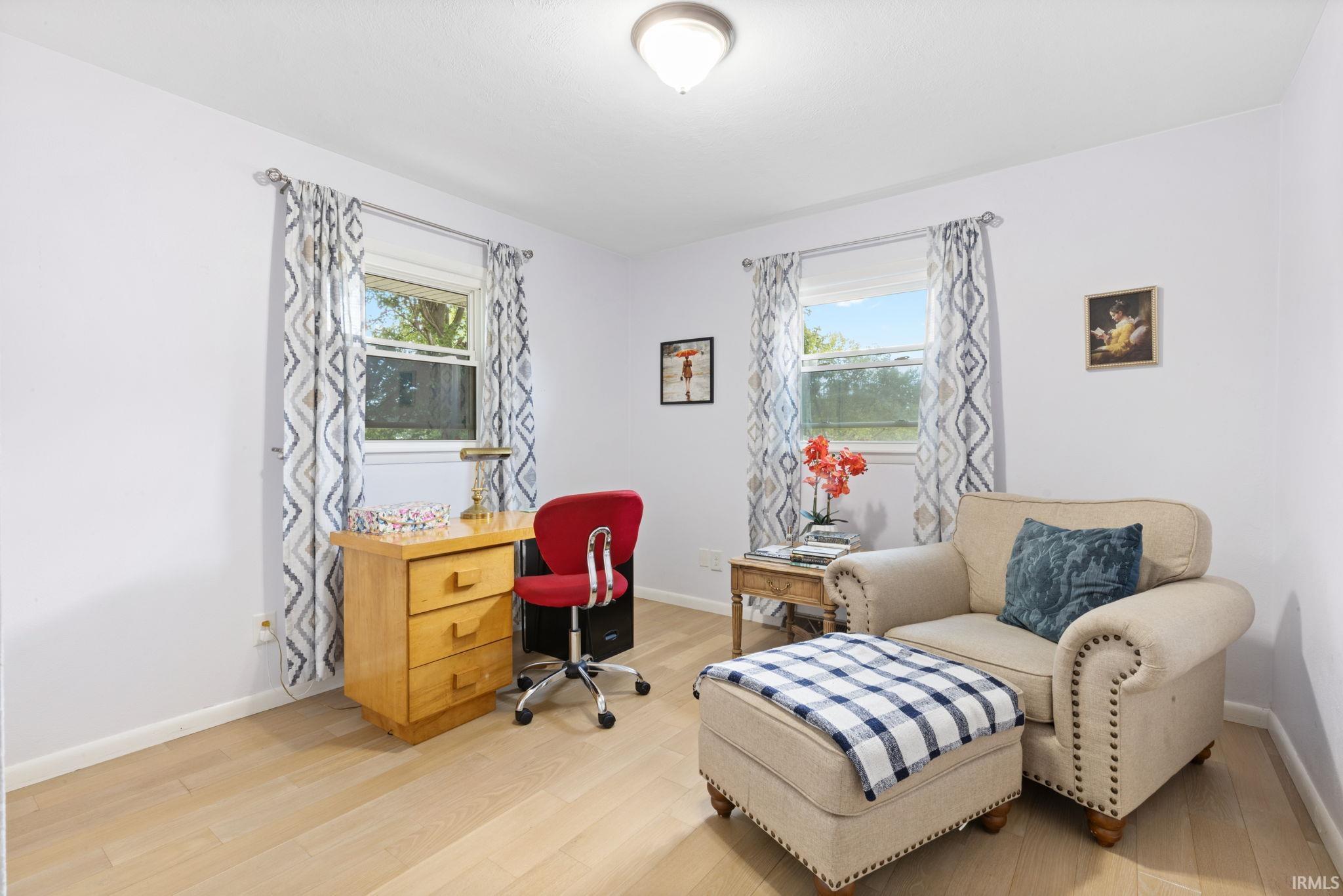 Light wood-finish flooring, two windows with natural light, and a ceiling-mounted light fixture