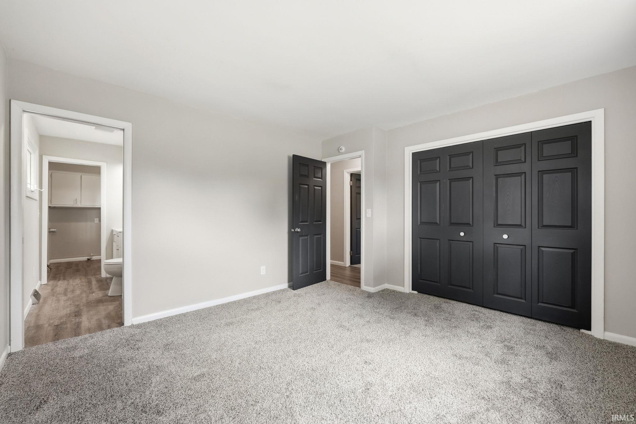 Plush grey carpeting, light grey wall paint, and black paneled doors