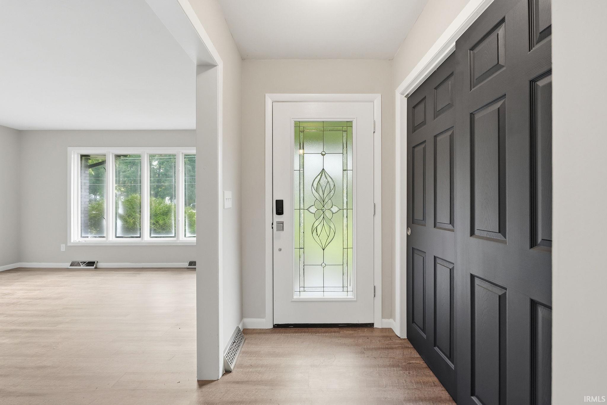 Entryway featuring a decorative glass front door, dark paneled closet doors, and wood-finish flooring