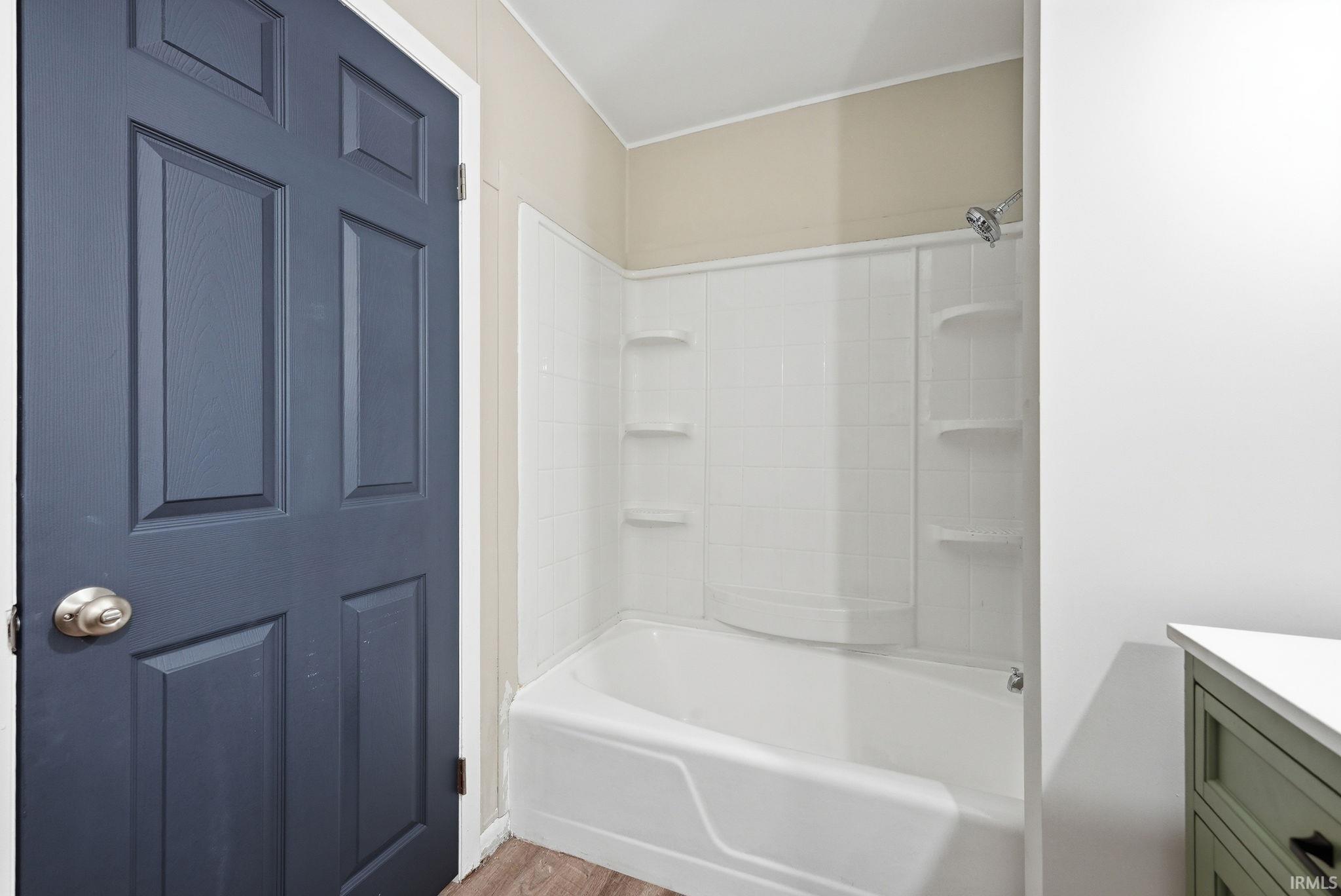Tub-shower combination with a white surround and integrated shelving