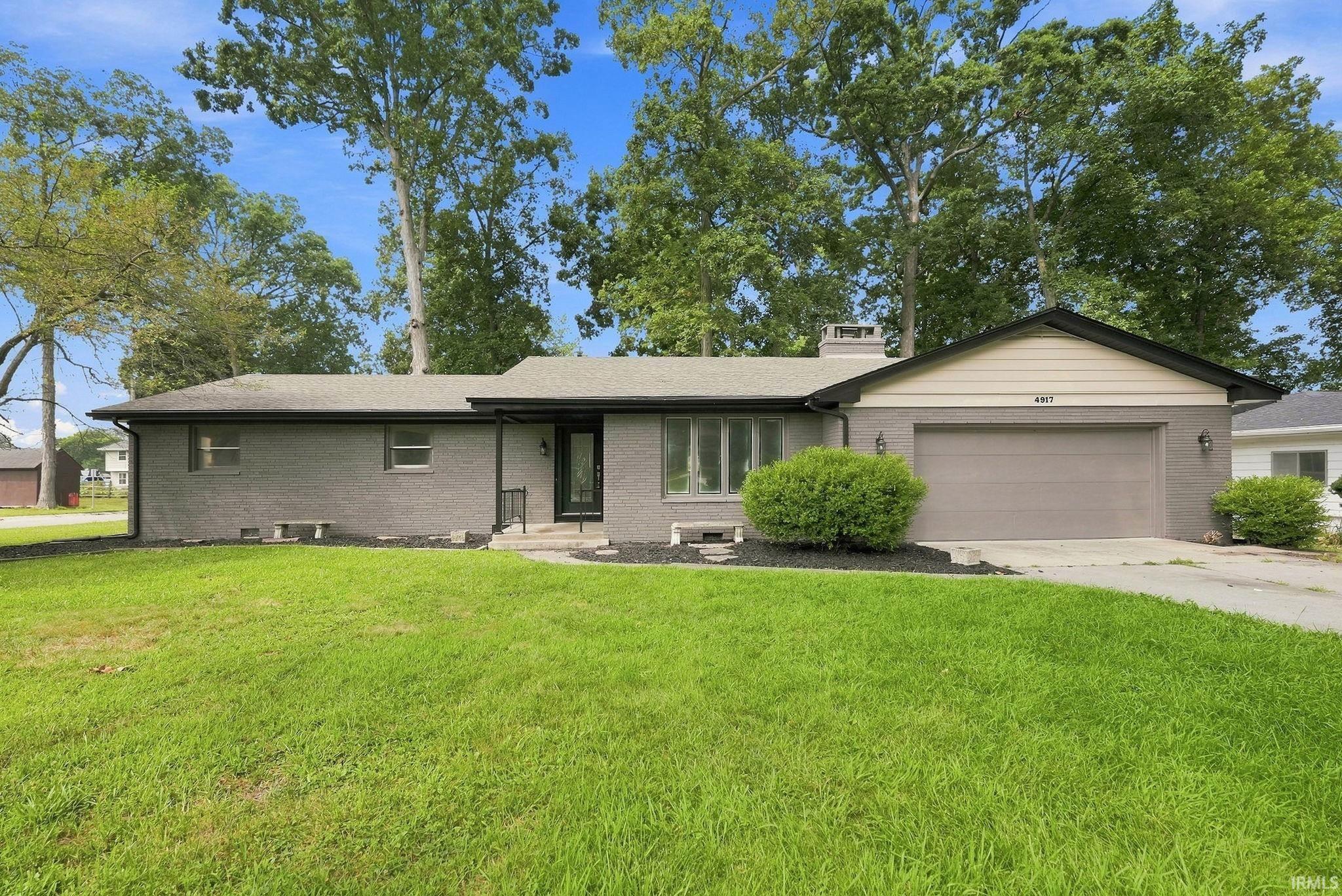 Single-story residence featuring a brick exterior and an attached garage with a paved driveway