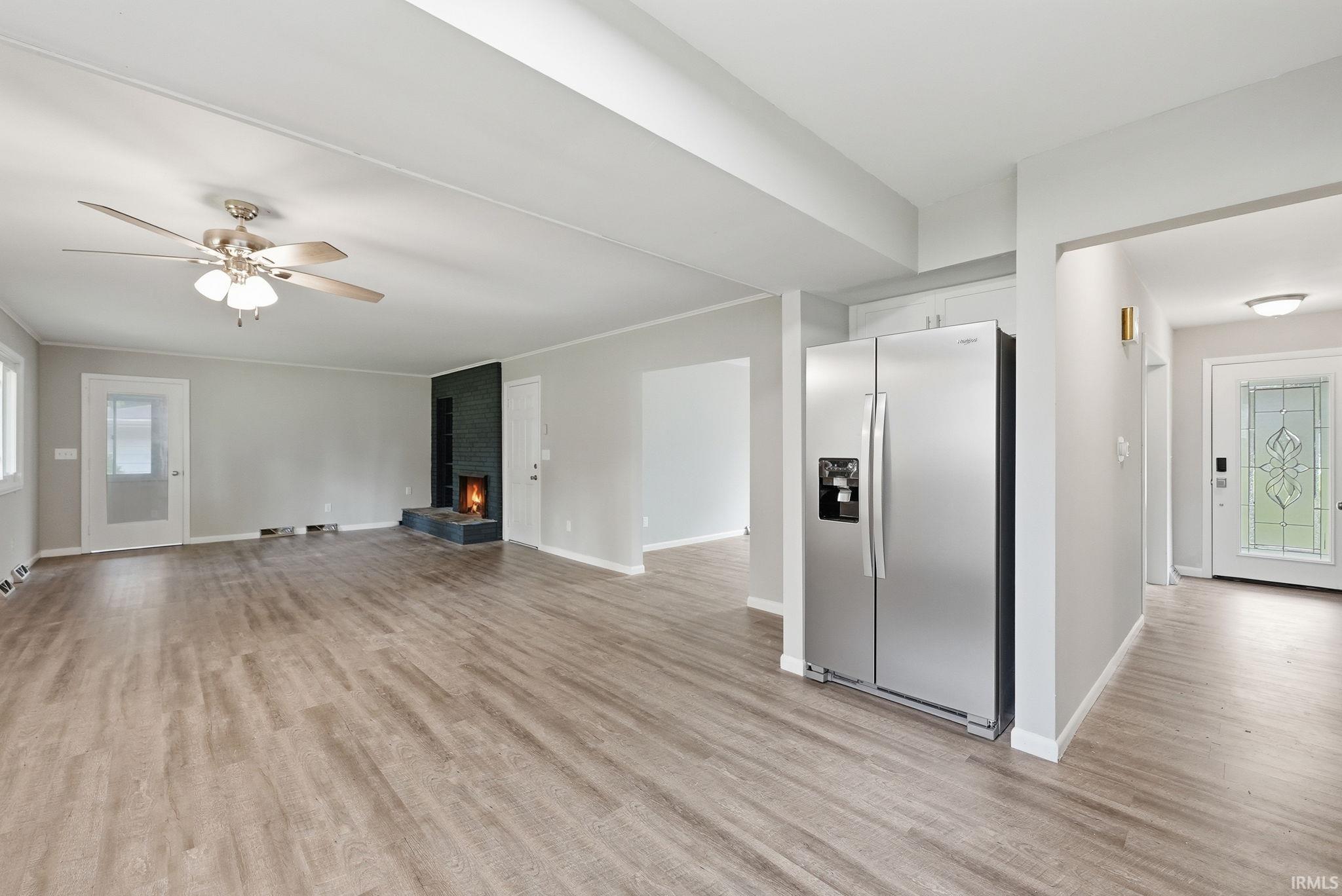 Open-concept living area with wood-finish flooring, a contemporary fireplace, and a ceiling fan