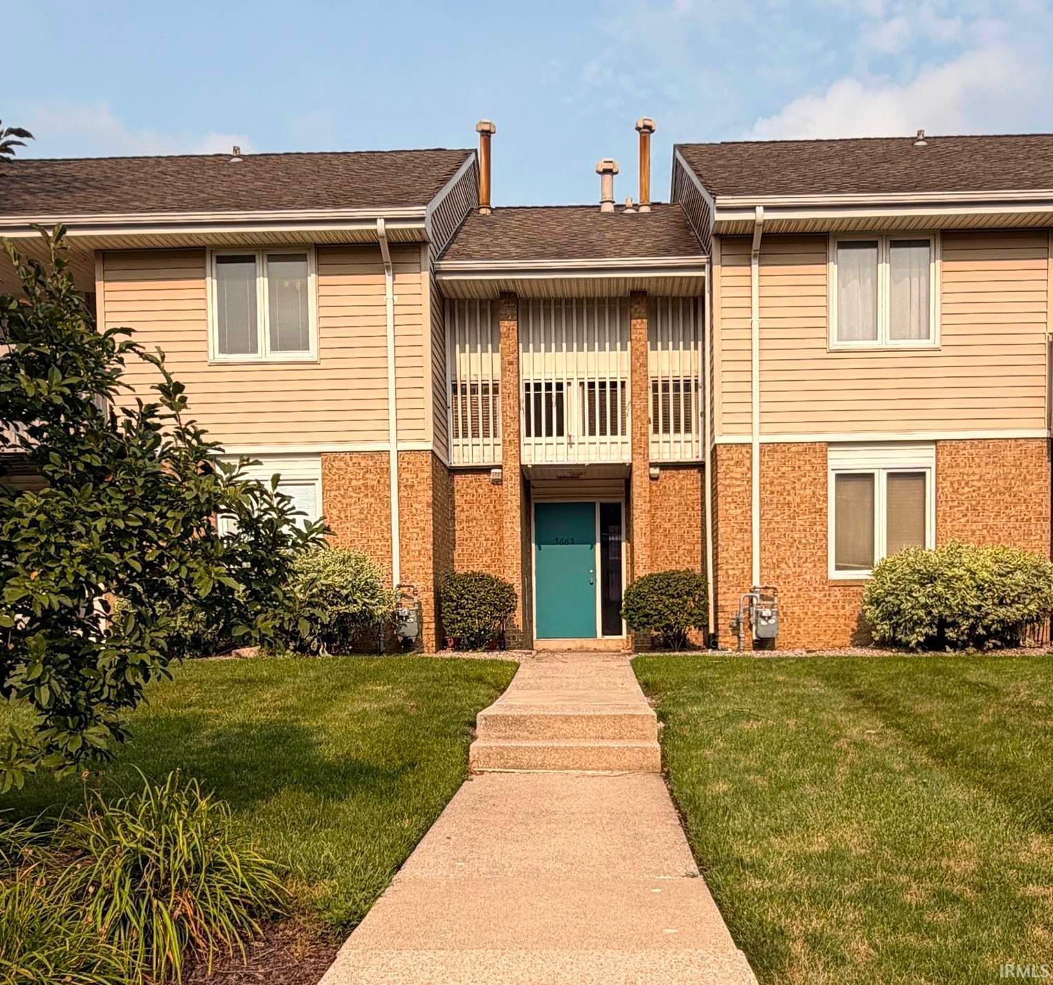 Multi-level residential building with beige siding and brick facade